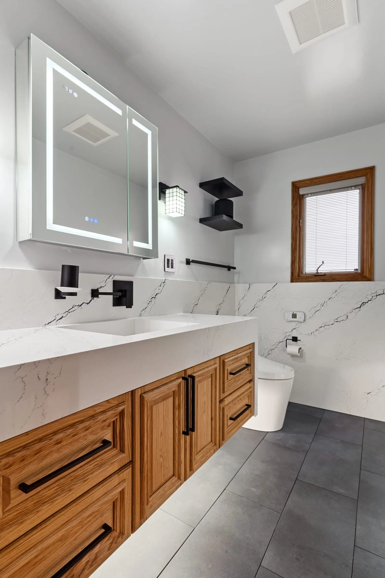 Backlit mirror cabinet between matte black wall sconces