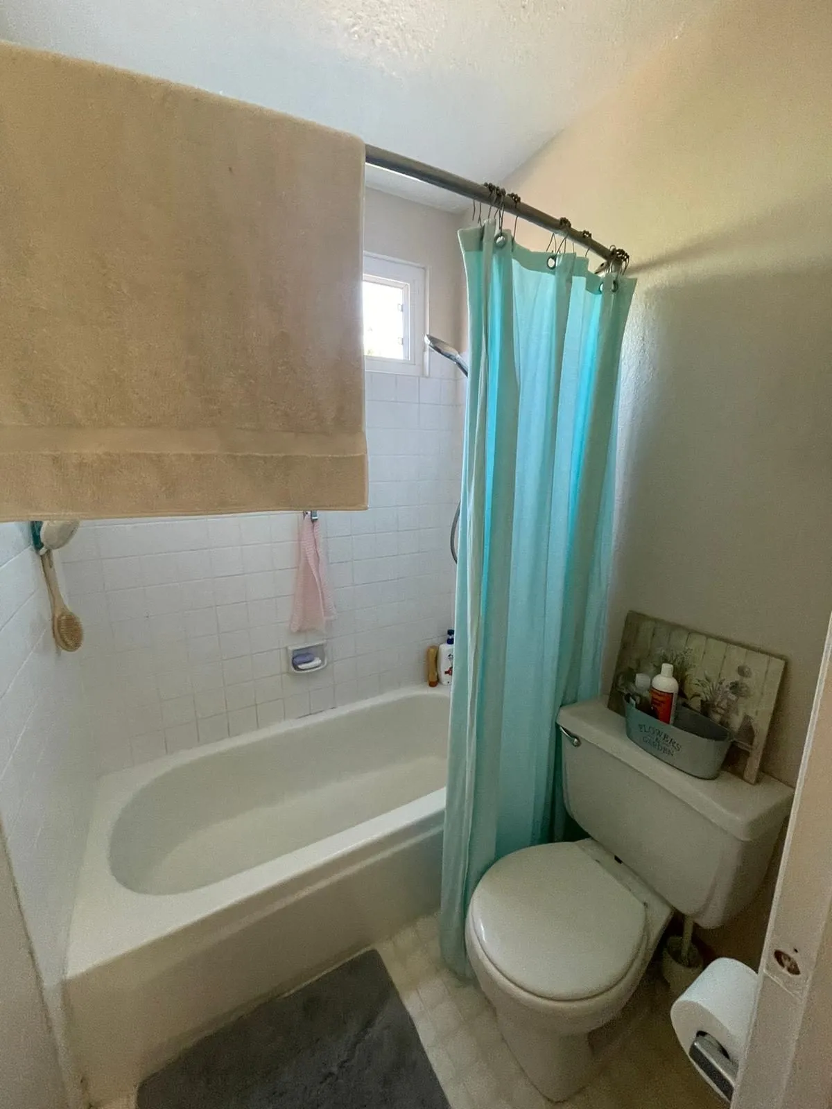 Original bathroom before remodel, alcove tub with a fabric shower curtain and tiled surround