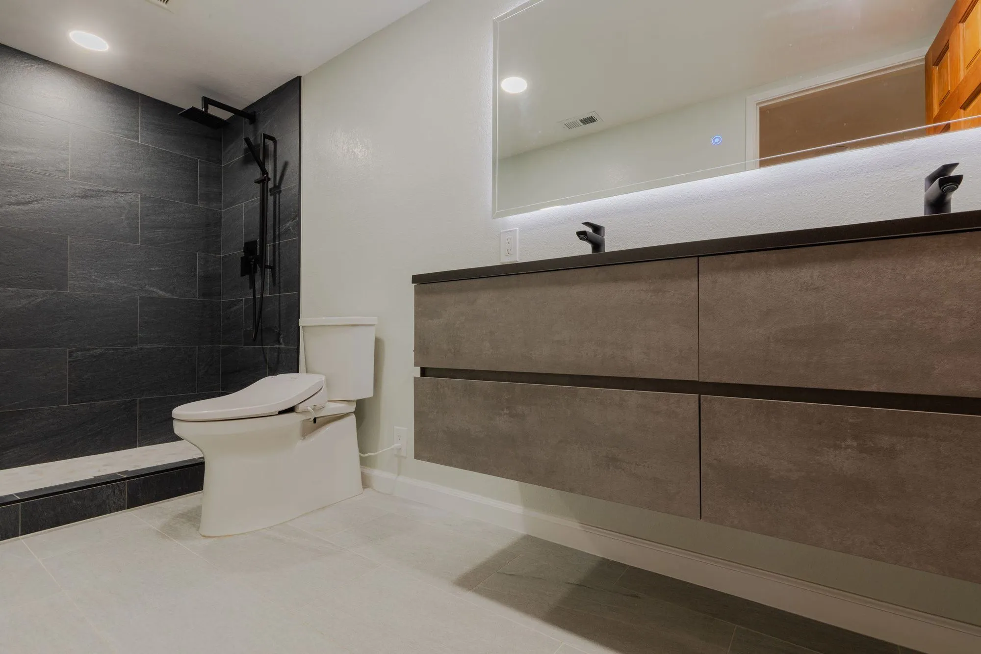 Bathroom with a wall-hung floating vanity against dark stone-look tile
