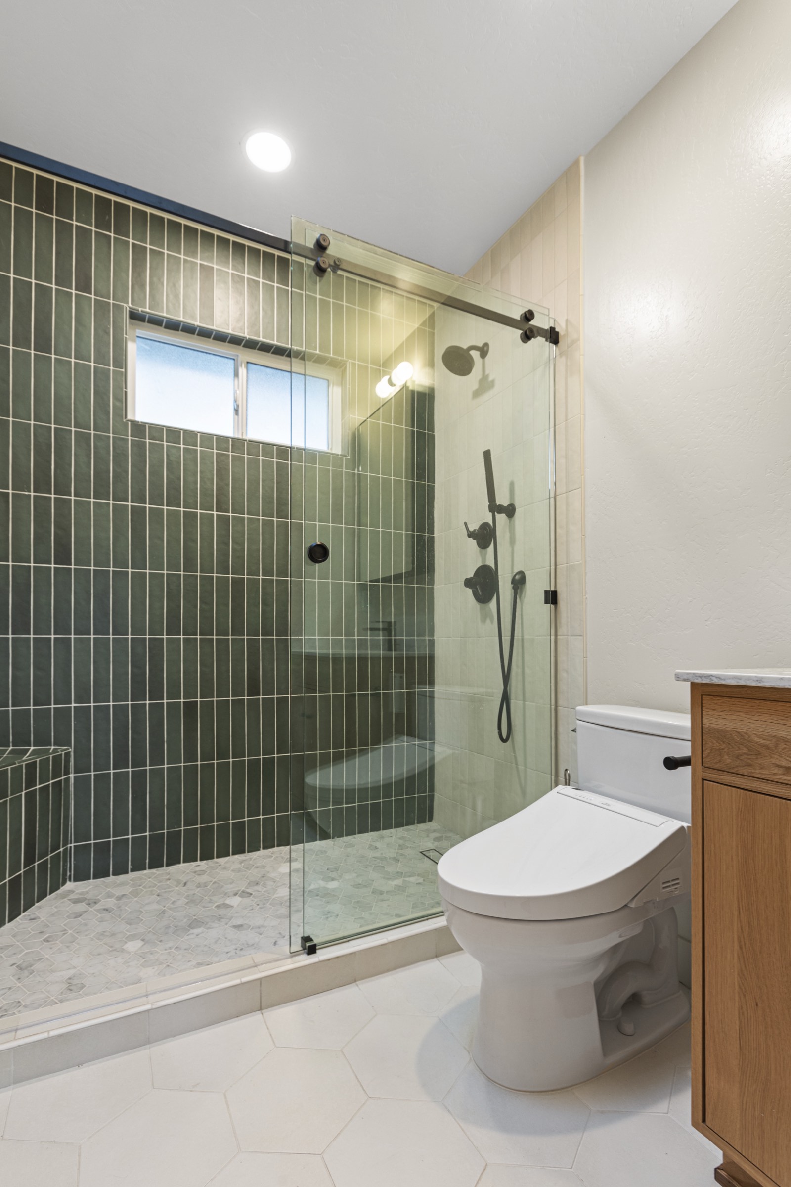 Bathroom with green vertical stack tile shower, glass door, and hexagon floor tile