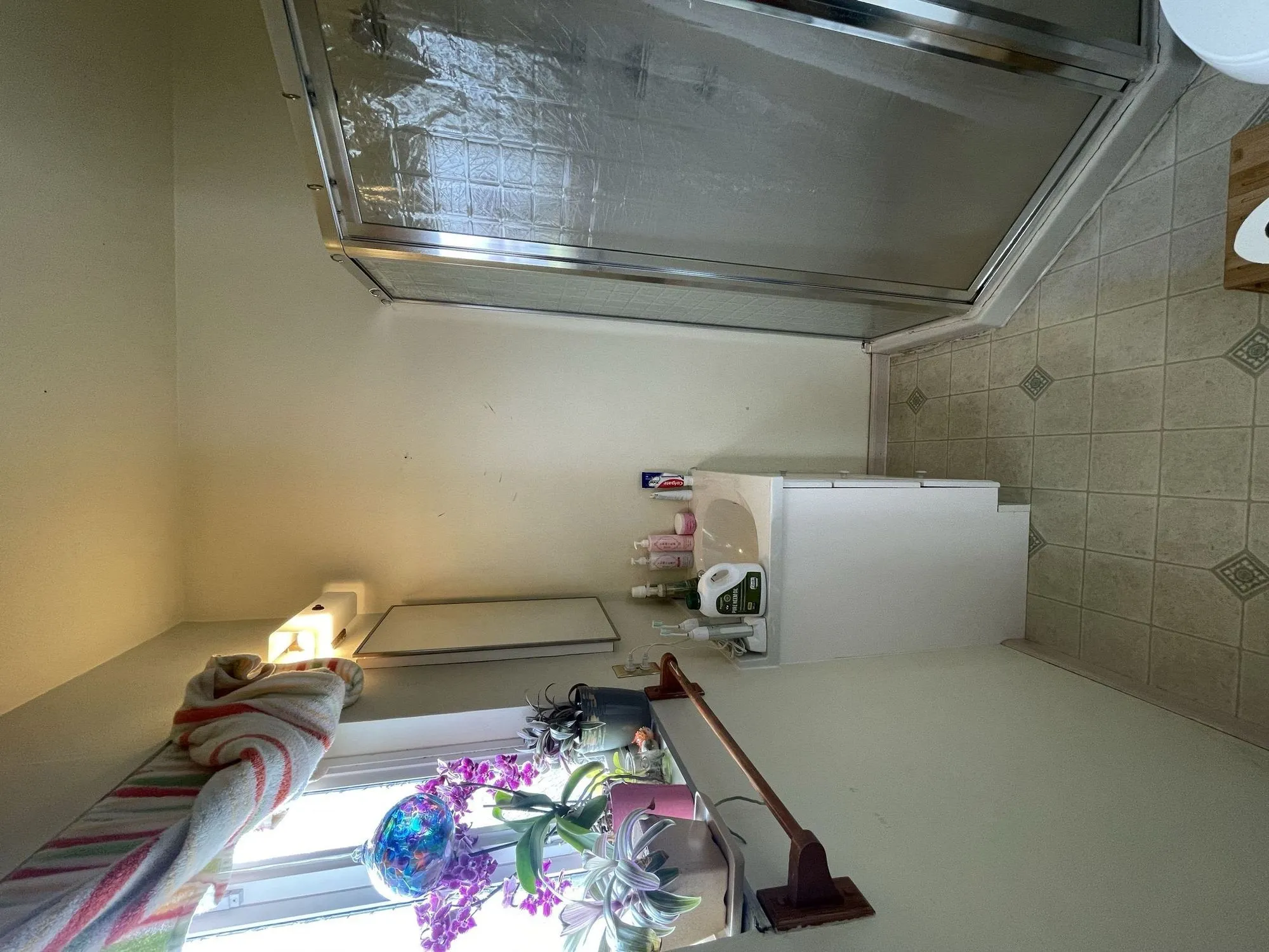 Original bathroom before remodel, framed glass shower stall and small vanity