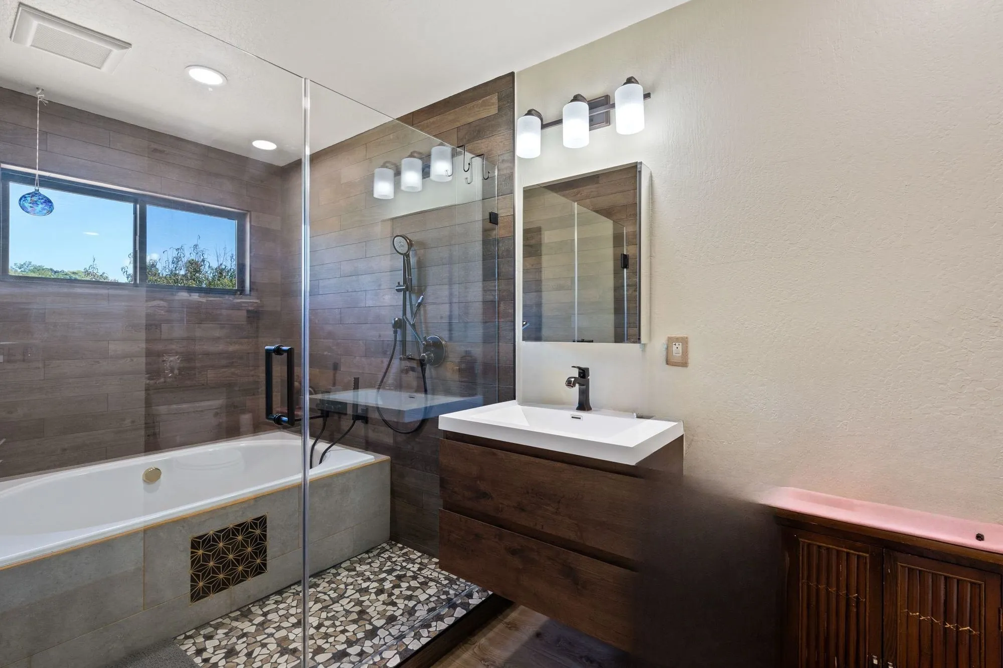 Bathroom after remodel, wood-look plank tile with drop-in soaking tub and glass shower panel