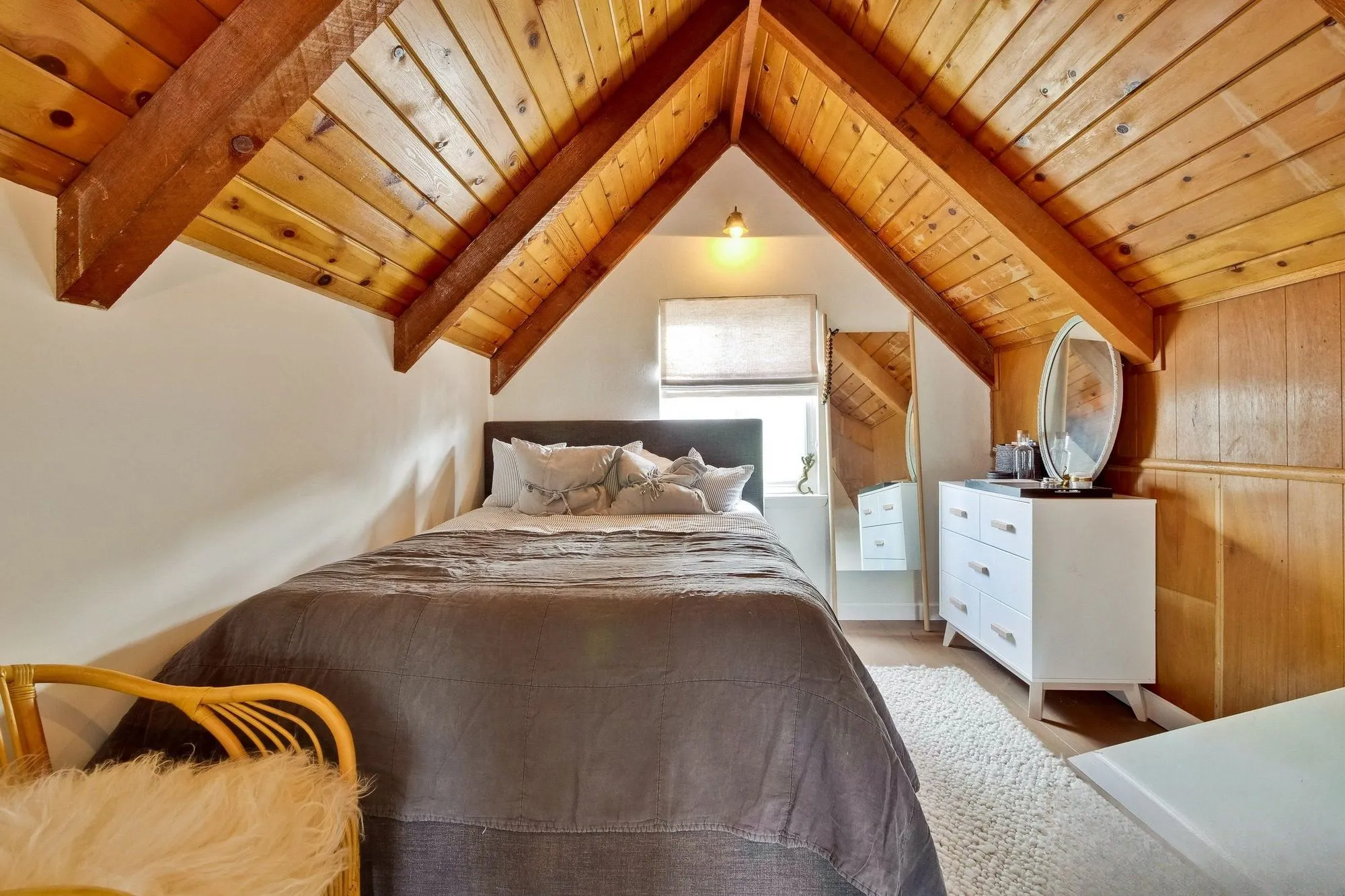 Bedroom lined in timber boarding under an exposed A-frame roof structure