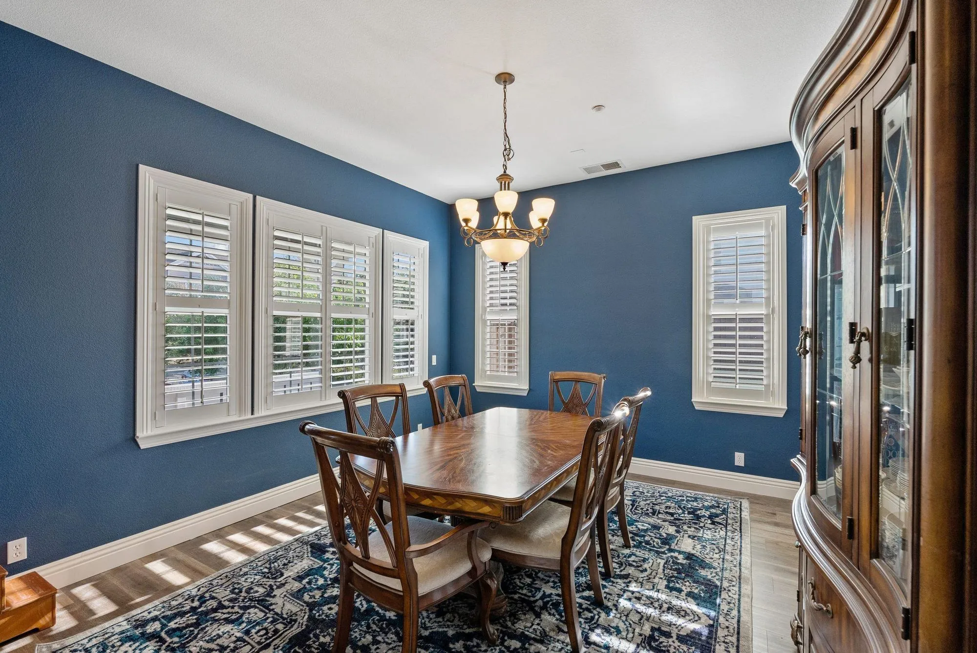 Dining room with deep blue walls, white plantation shutters and a timber hutch