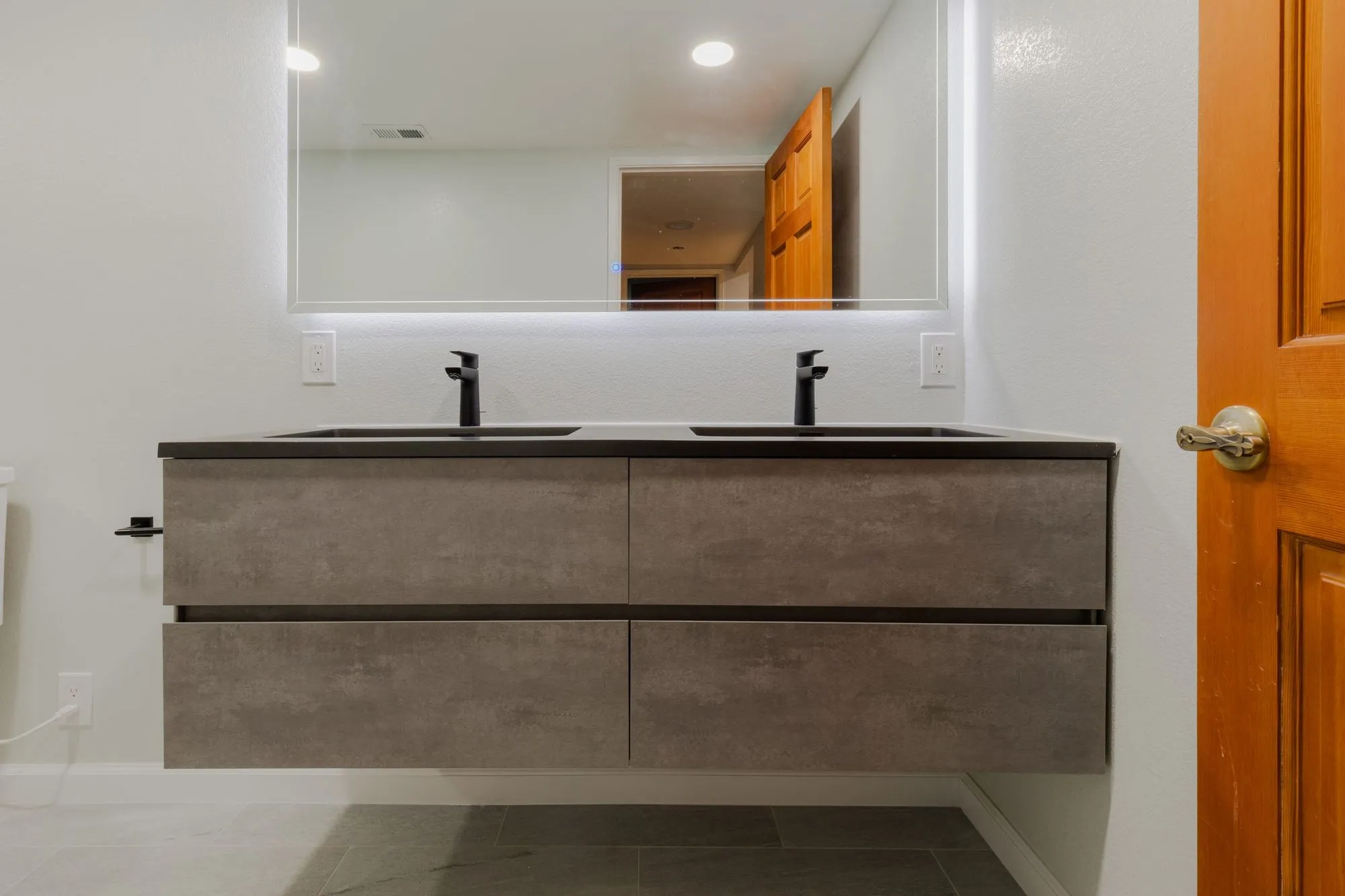 Floating double vanity with twin basins below a backlit mirror