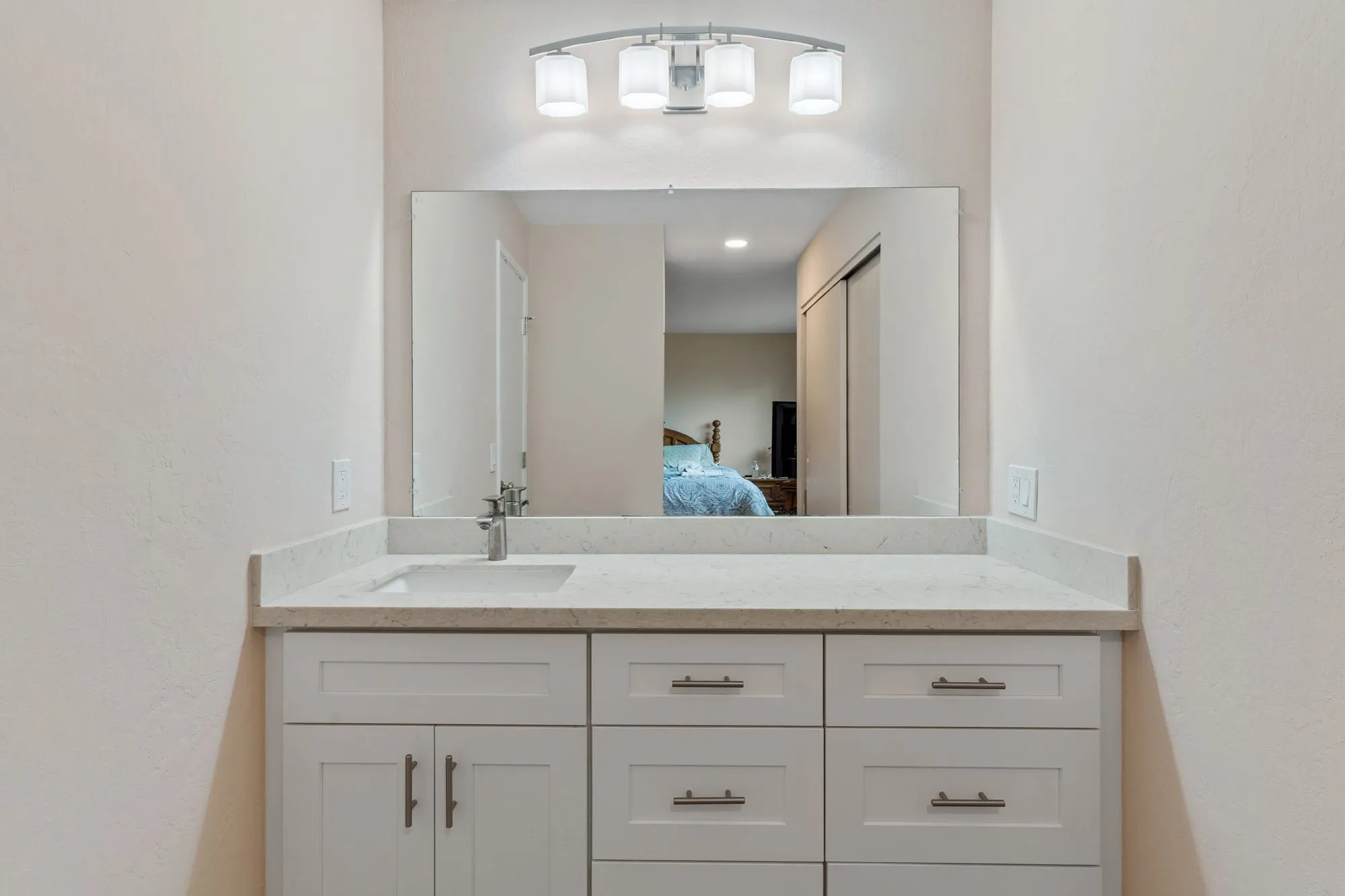 Double vanity in white shaker cabinetry with a quartz top and full-width mirror