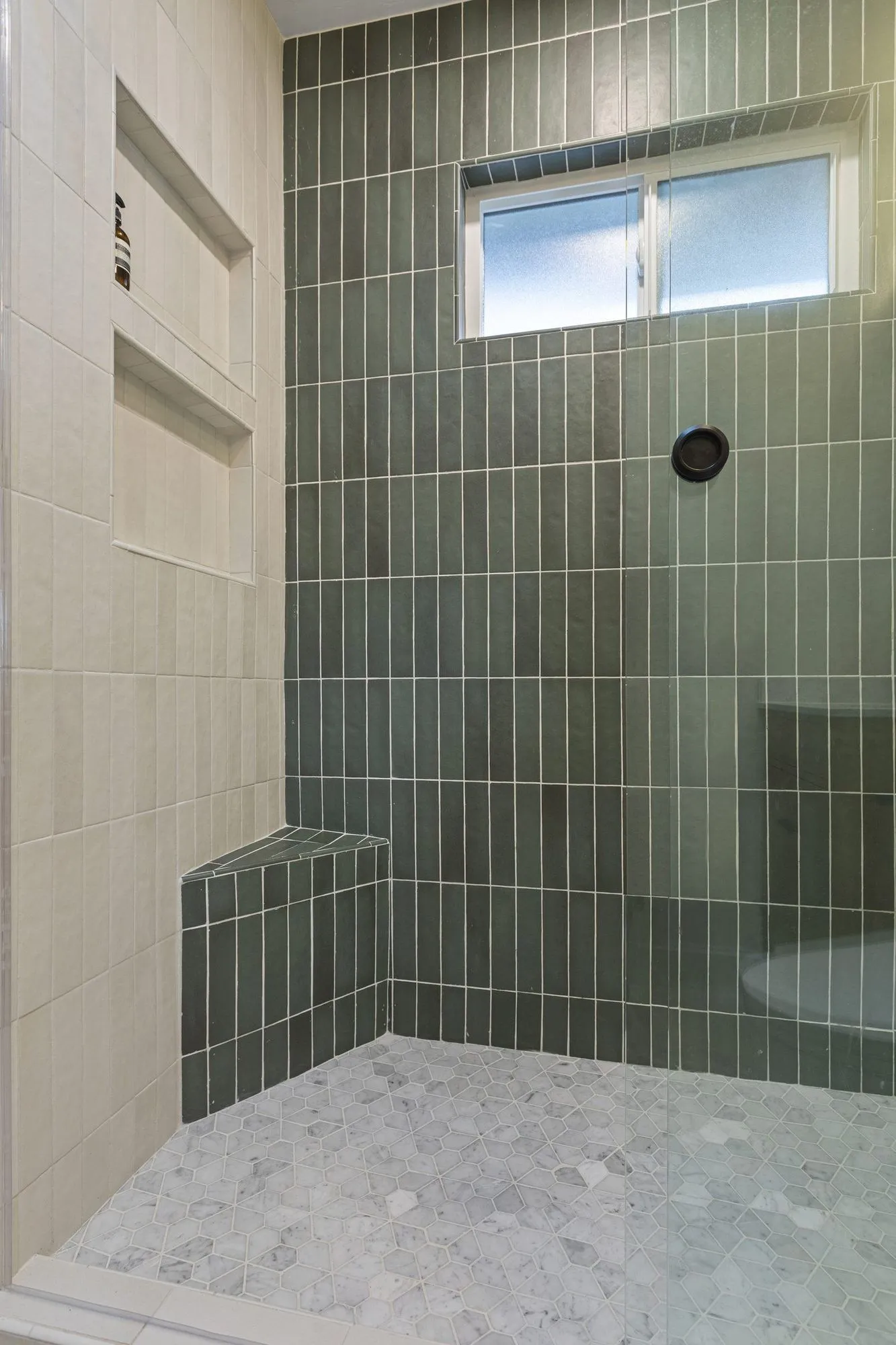 Shower bench and recessed niche set into the sage-green stacked tile