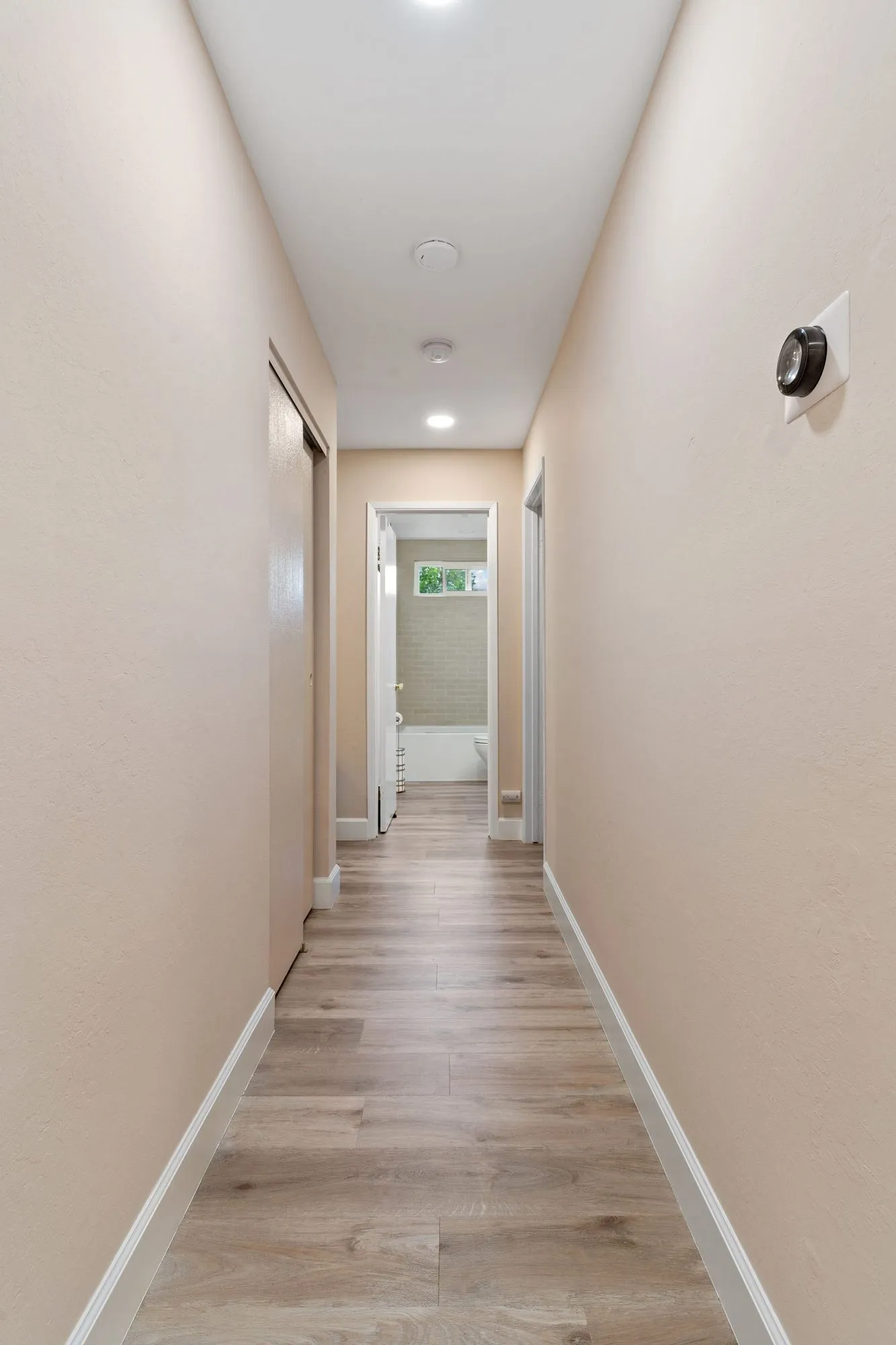 Hallway with light wood-look plank flooring and recessed ceiling lights