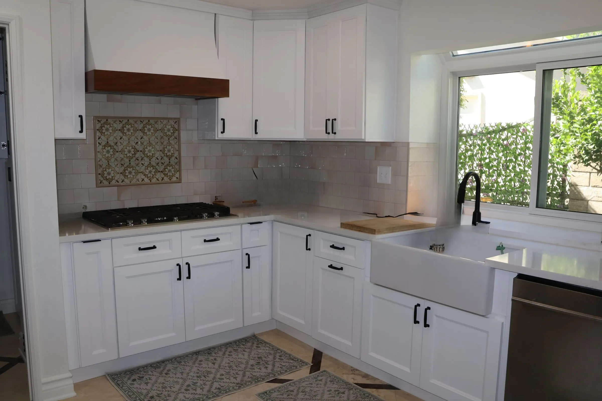 Full L-shape kitchen — wood hood, encaustic tile, apron sink, subway tile, patterned floor