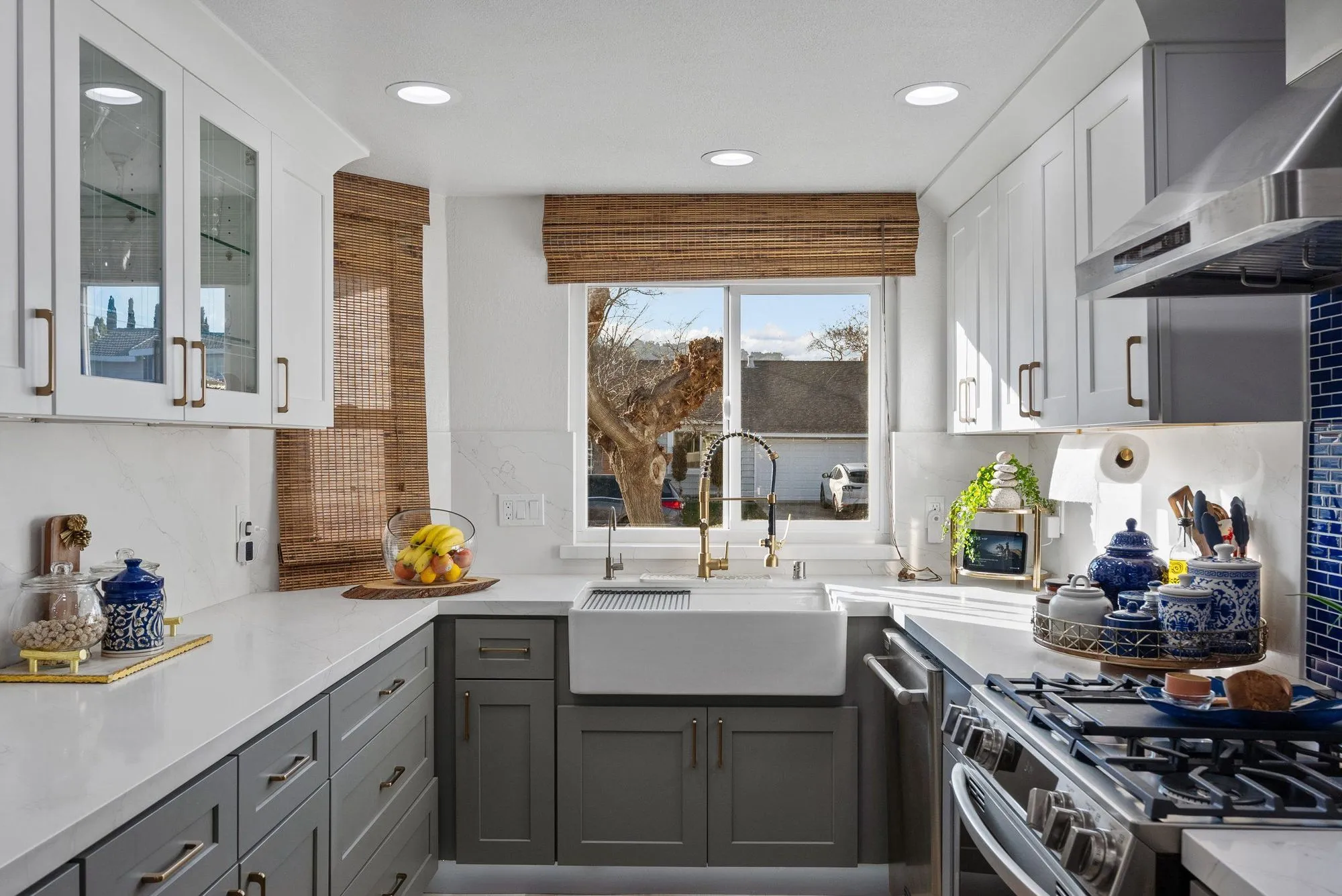 Kitchen after whole-home remodel, white uppers over charcoal lowers with a cobalt glass tile backsplash