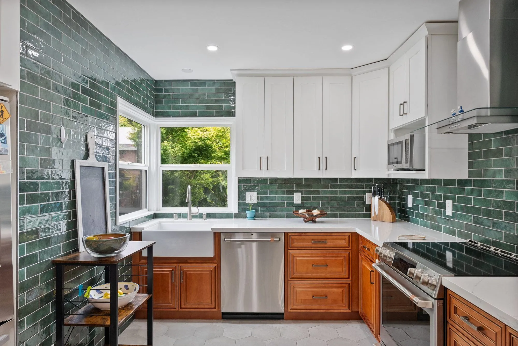 Kitchen after whole-home remodel, deep green tile above timber lower cabinets with white shaker uppers