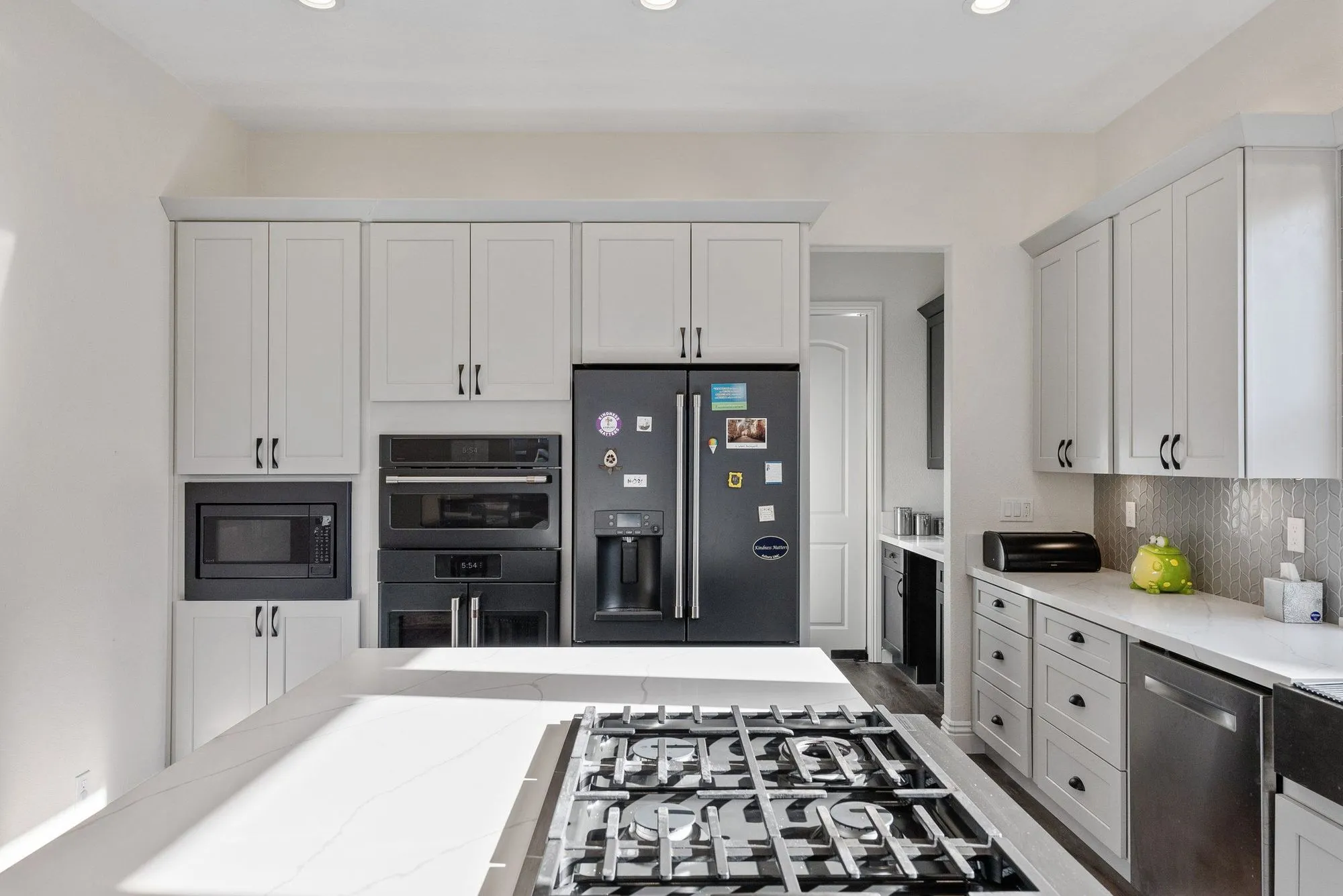Tall cabinet run with a black french-door refrigerator and stacked wall ovens