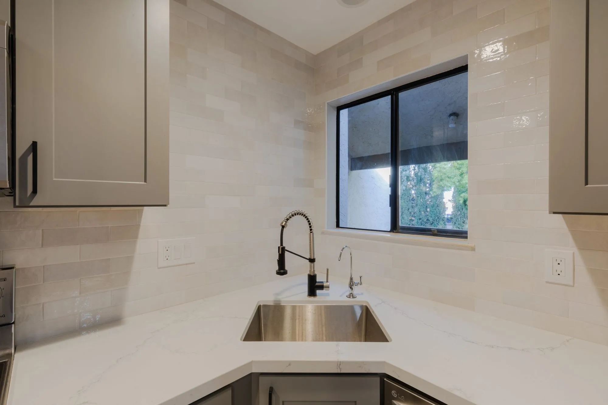 Corner sink set below the window with a matte-black gooseneck tap