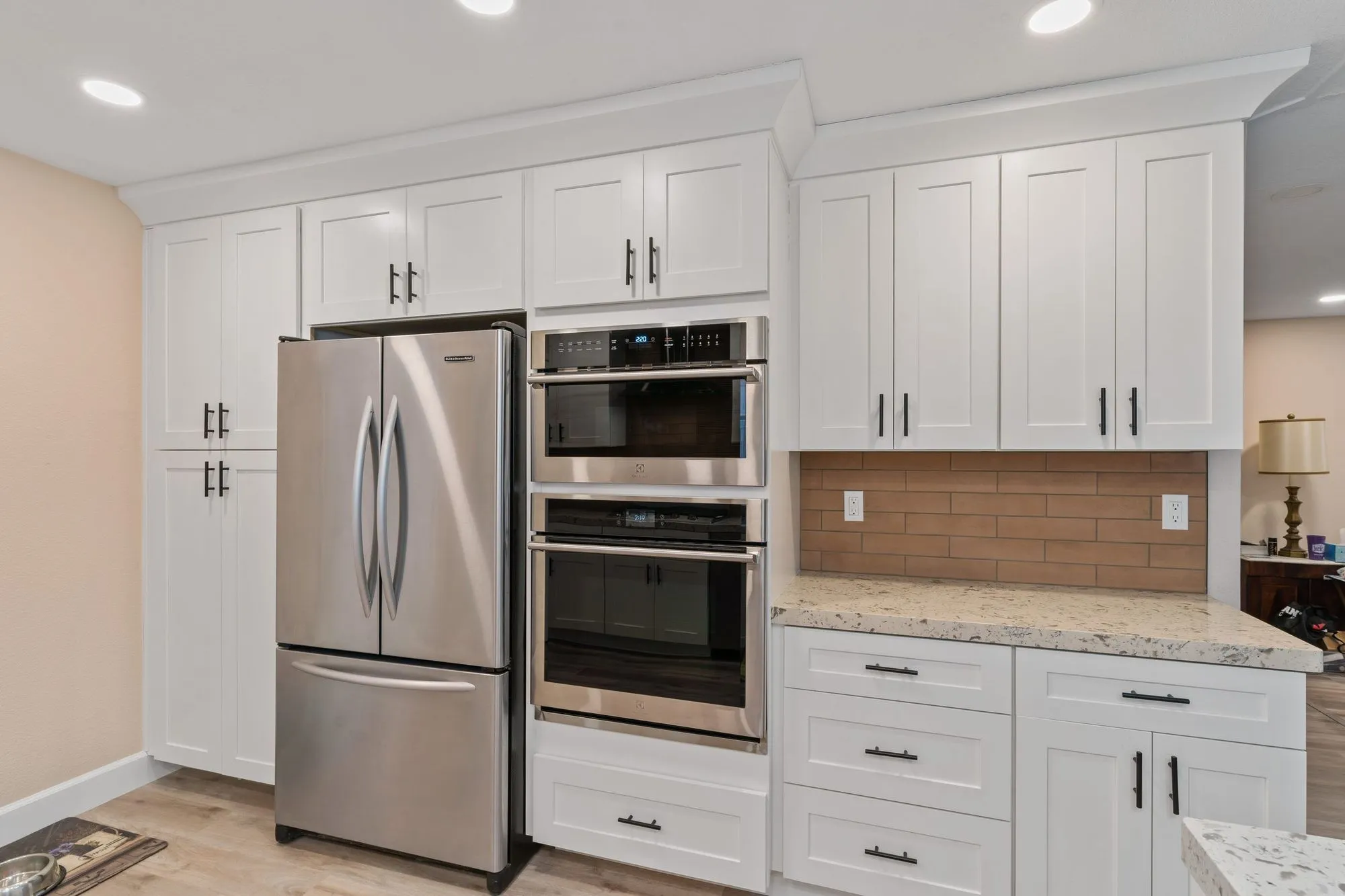 Tall cabinet run with a stainless french-door refrigerator and stacked wall ovens