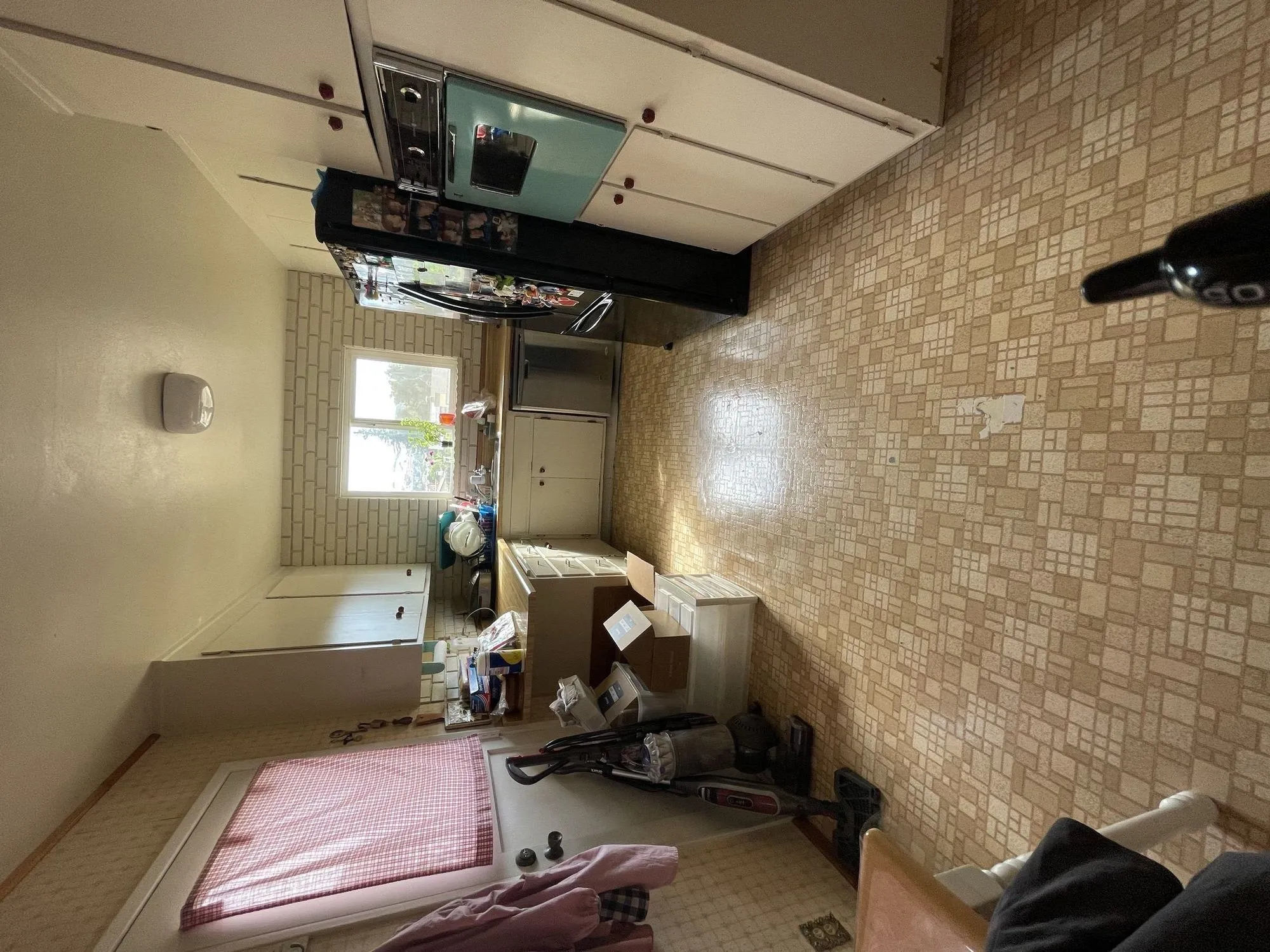 Original galley kitchen before remodel, cream cabinets and patterned vinyl flooring