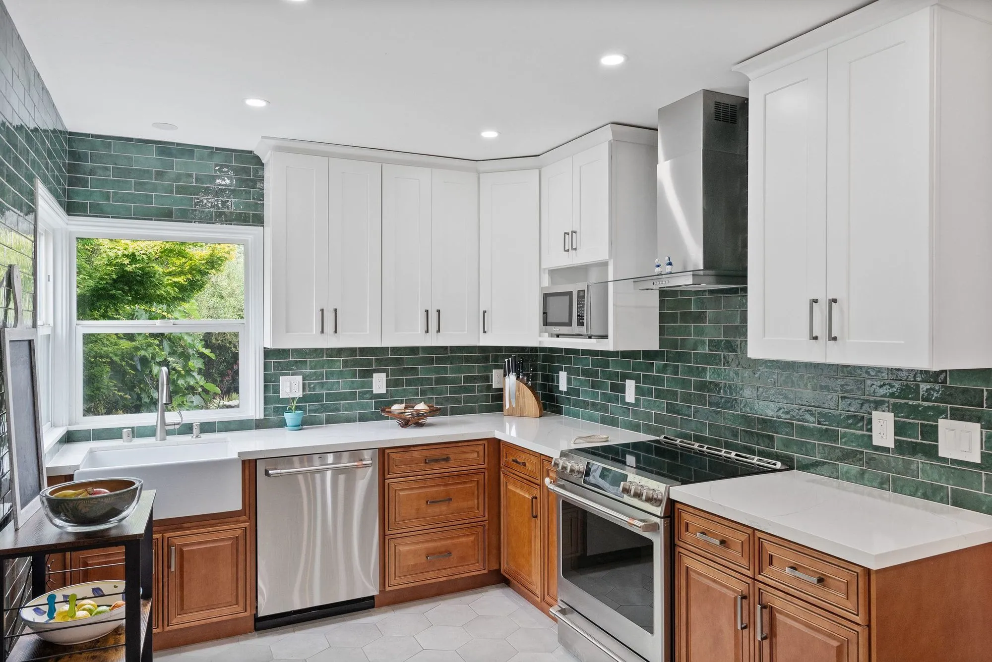 Kitchen in deep green tile with a white apron-front farmhouse sink below the window