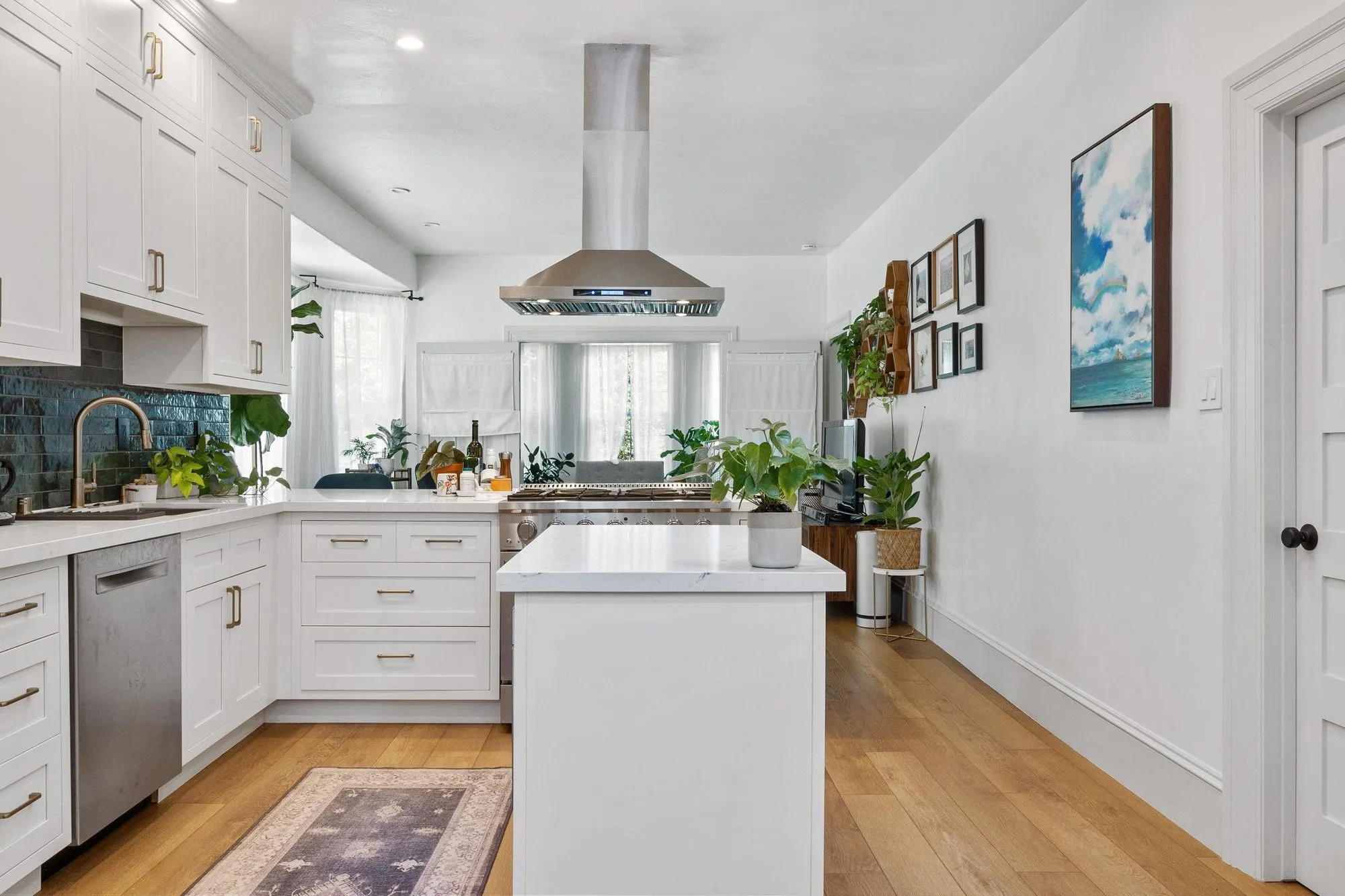 Kitchen island and range run with framed artwork lining the wall above the counter