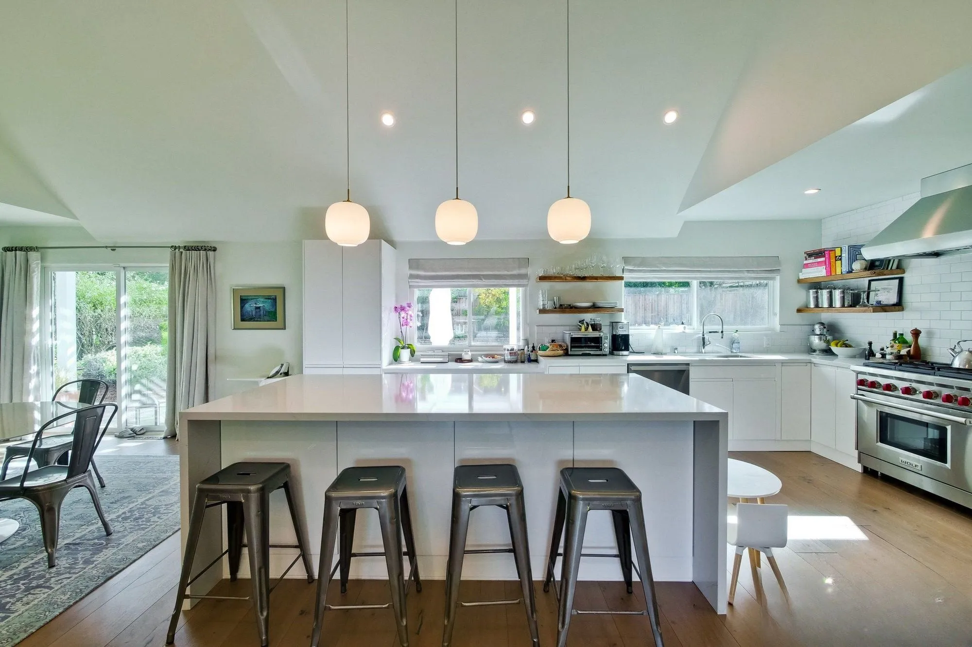 Kitchen island with bar stools, open to the dining area beyond