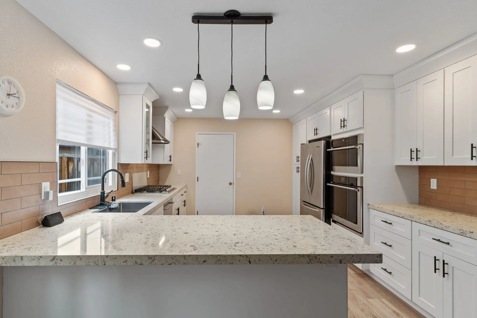 Kitchen peninsula with granite counter and a row of glass pendant lights above it