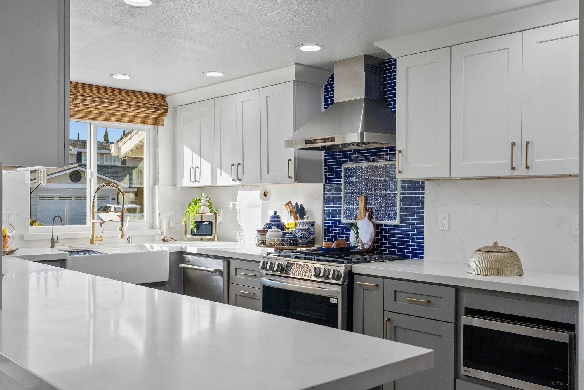 Wide kitchen view along the quartz counter run toward the range and hood