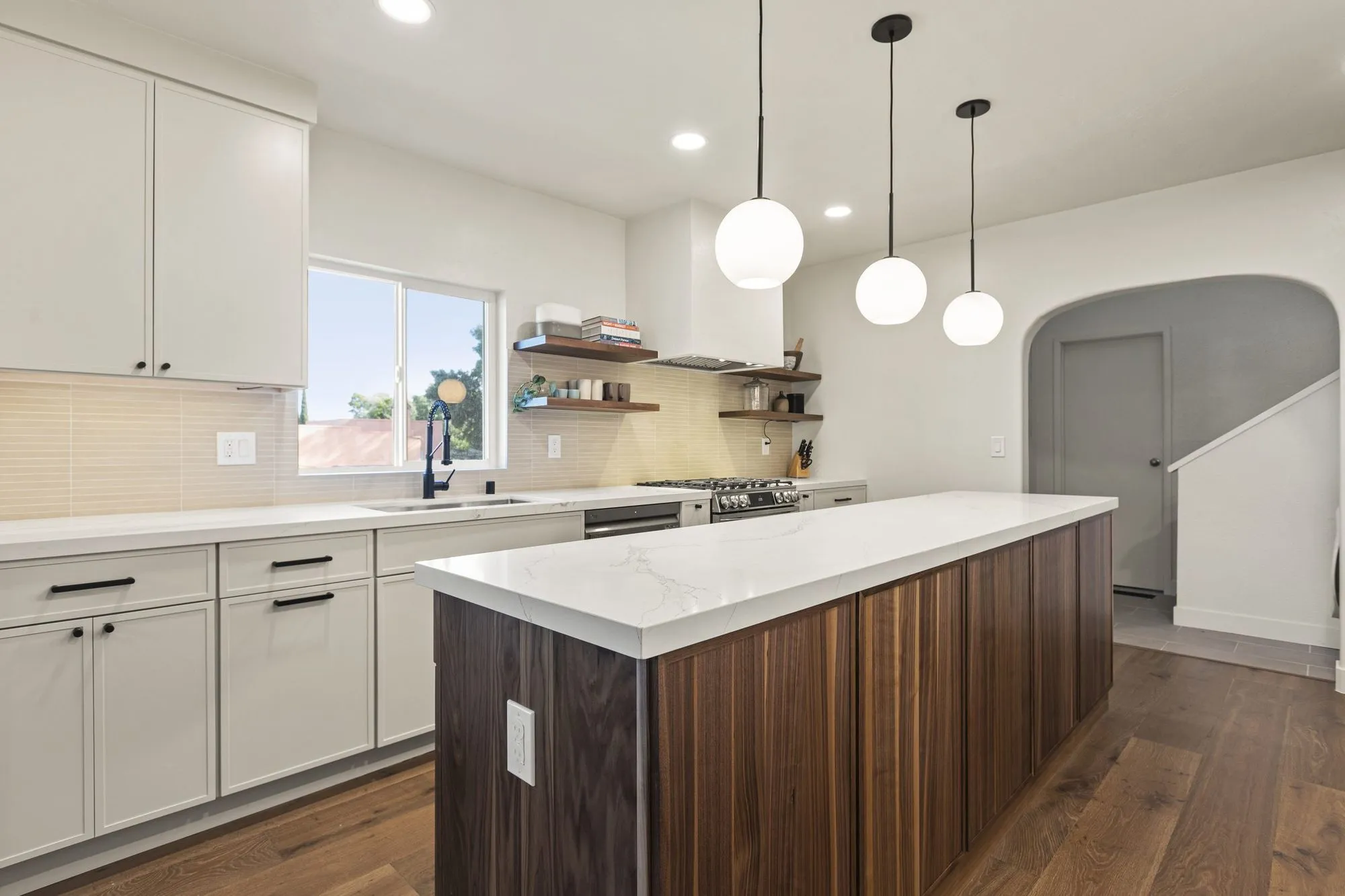Wide kitchen view along the quartz island toward the arched opening