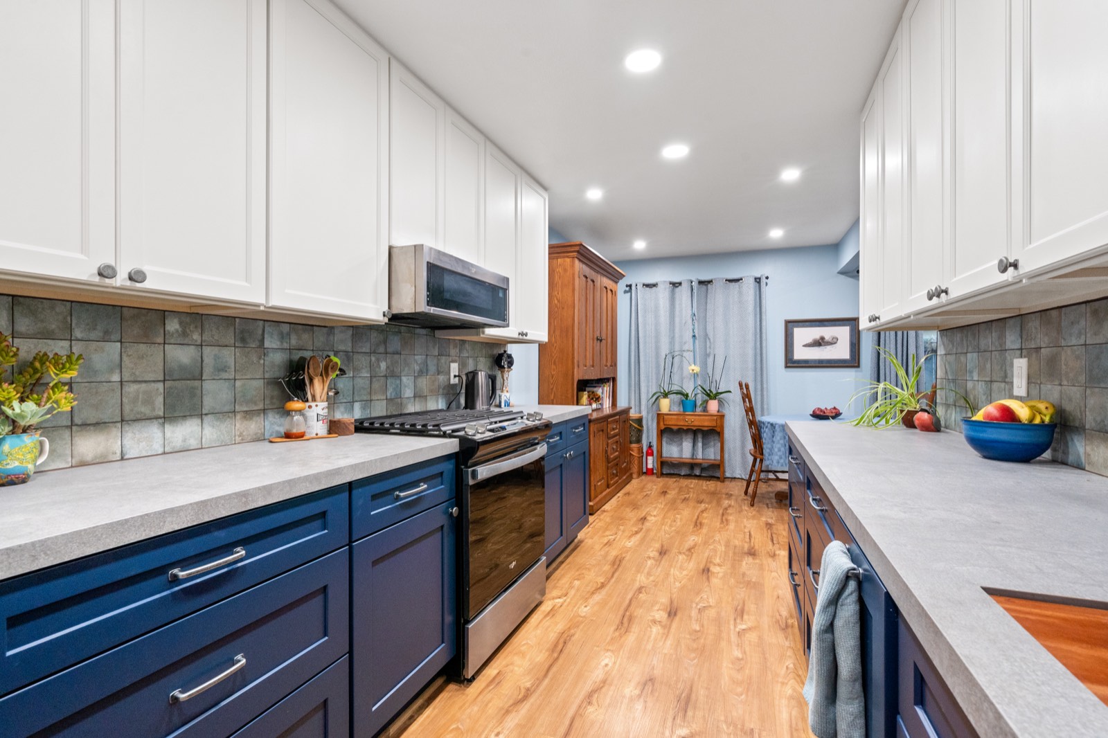 Navy blue and white galley kitchen with mosaic backsplash and quartz counters