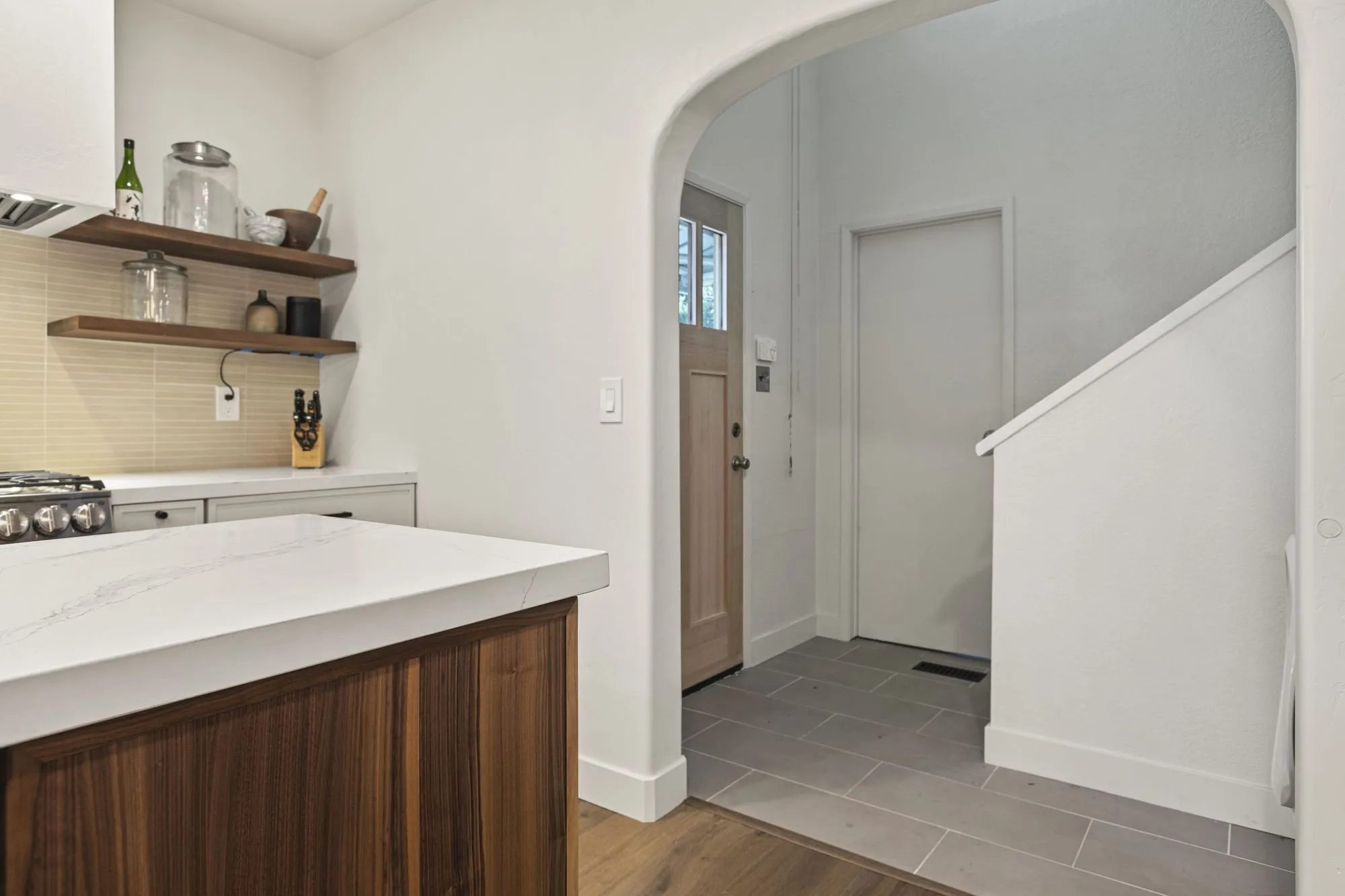 Open timber shelves above the counter beside an arched cased opening