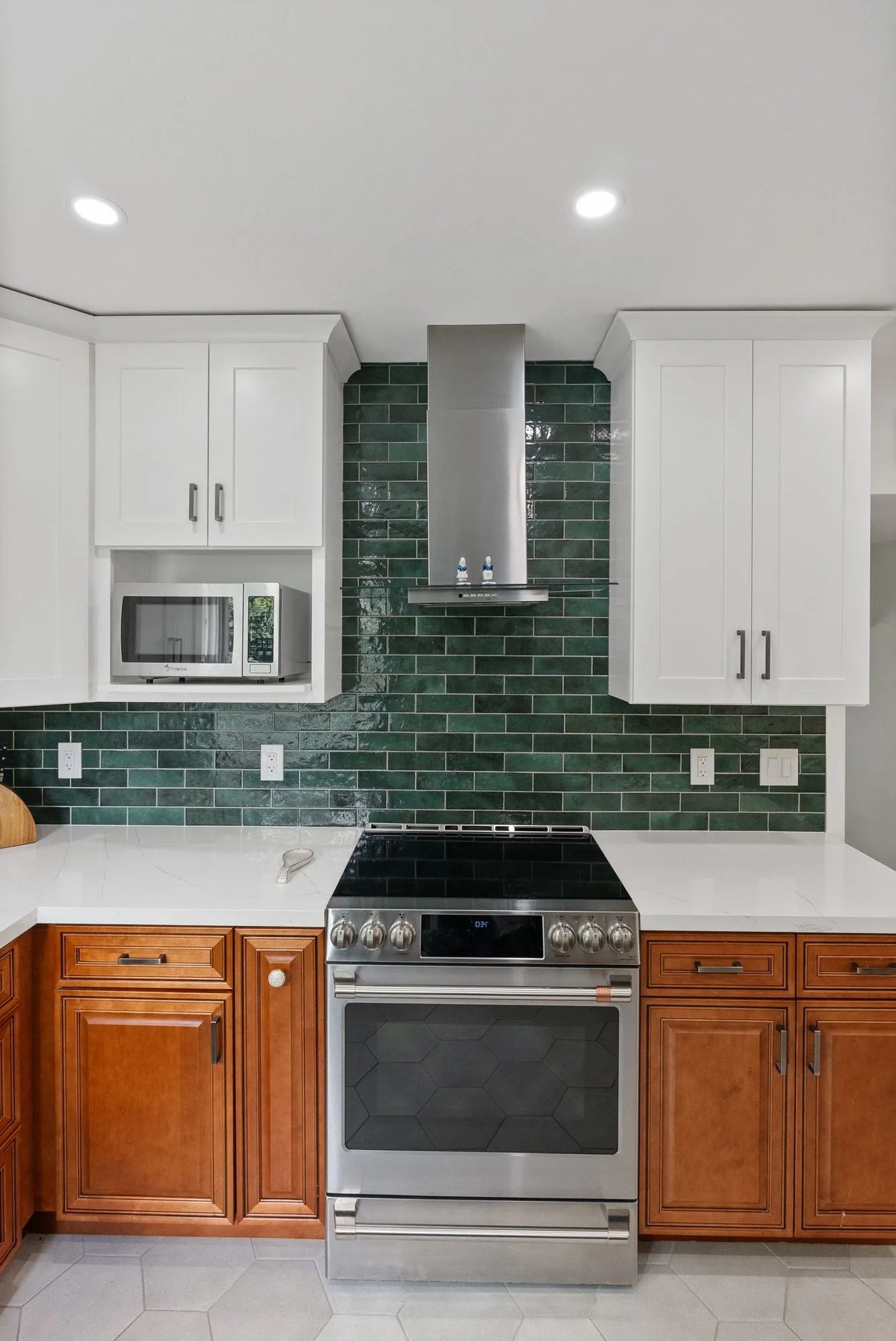Stainless range below a wall-mounted hood against the green tile wall