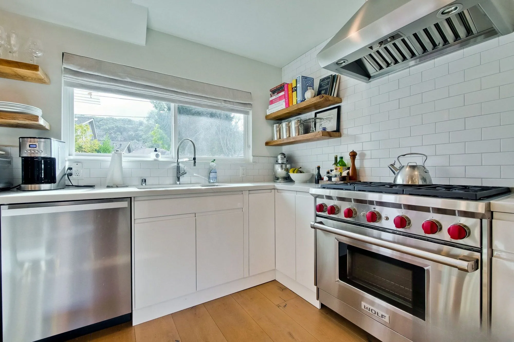 Stainless range below a wall hood, with open timber shelves stacked above the counter