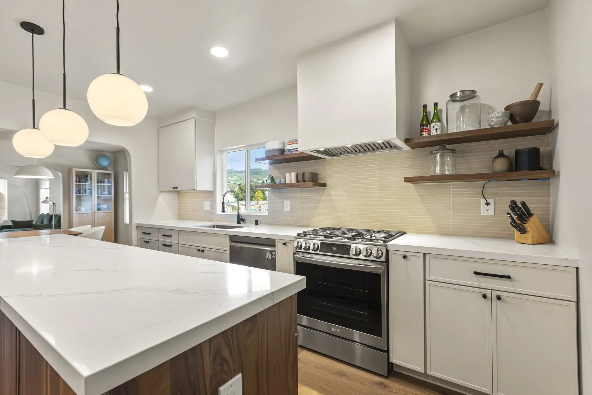 Stainless range set into the white cabinetry run beside the island