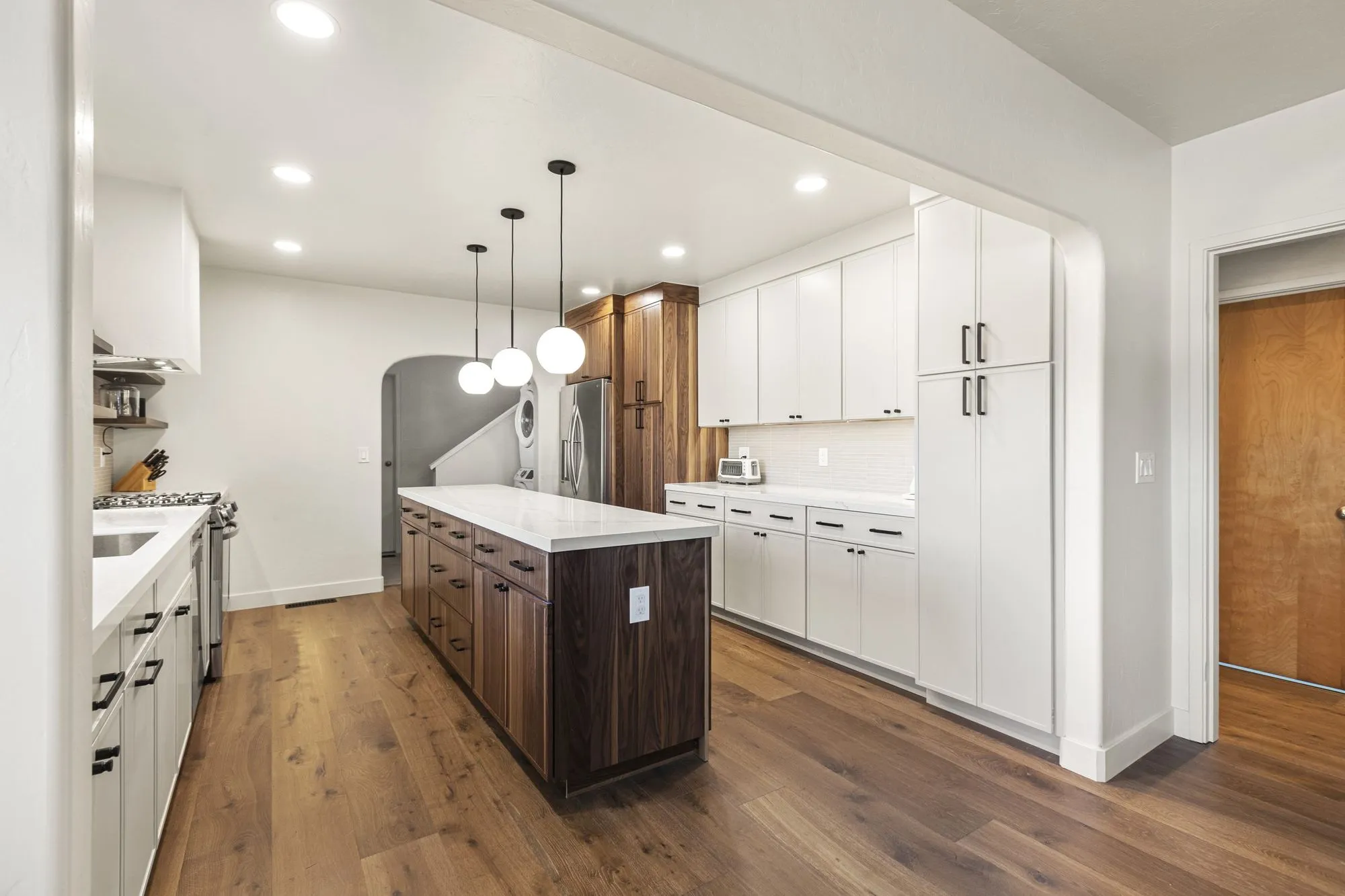 Walnut-fronted island with a quartz top under a cluster of globe pendant lights