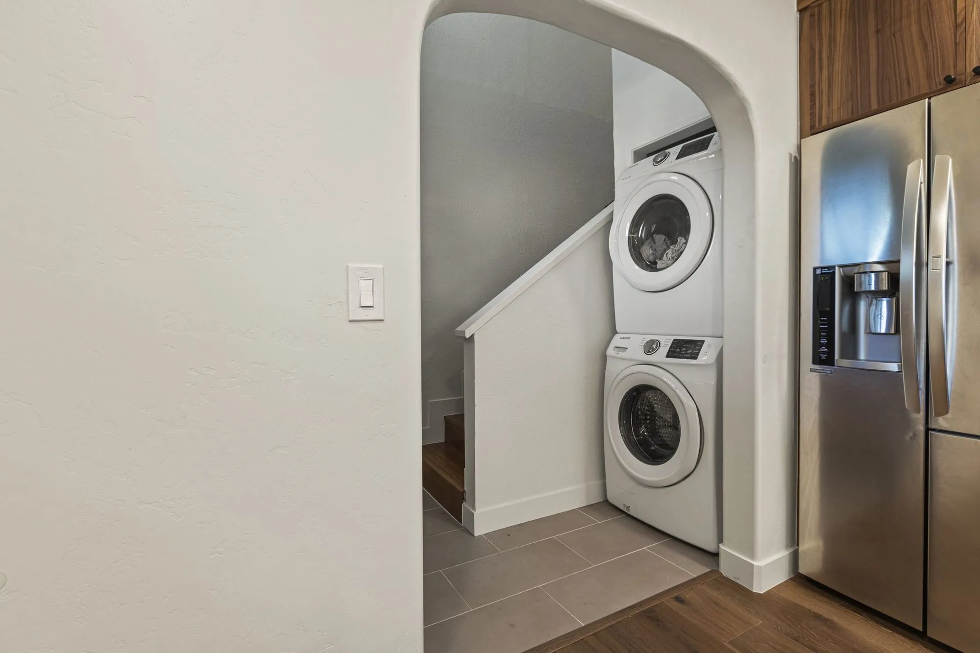 Stacked washer and dryer set into the space beneath the stair beside the refrigerator