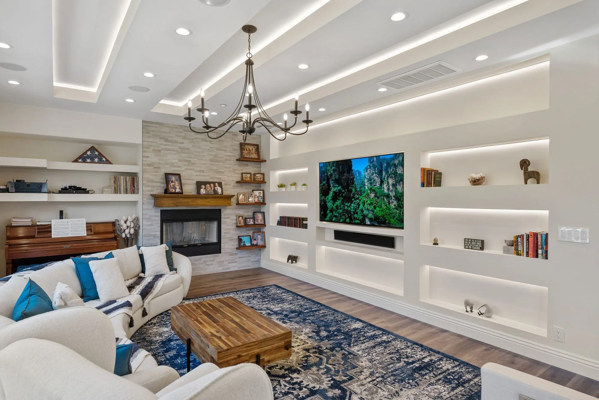 Living room with a linear fireplace set into white built-in shelving under a chandelier