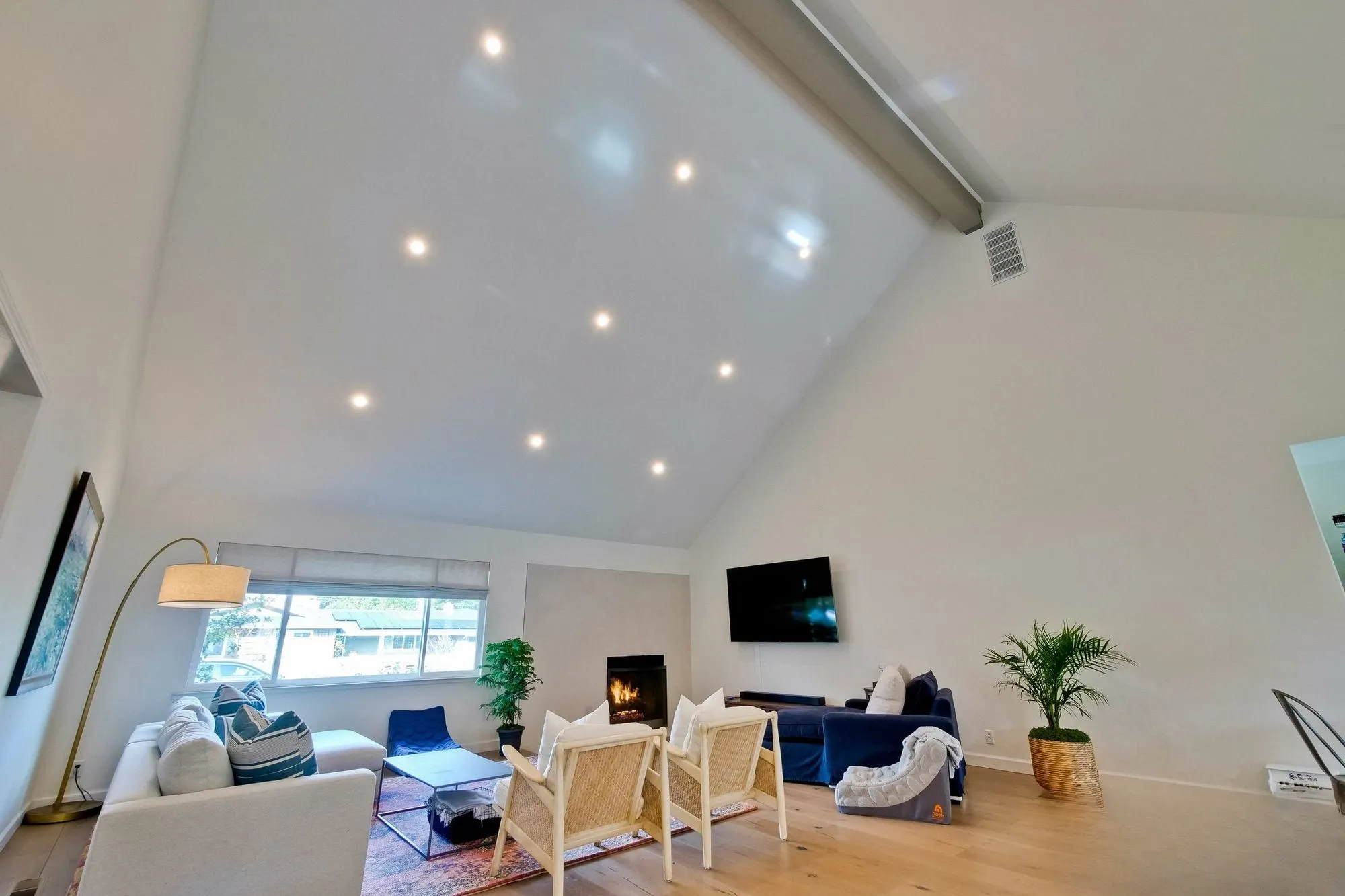 Living room with a fireplace, timber flooring and the kitchen visible beyond