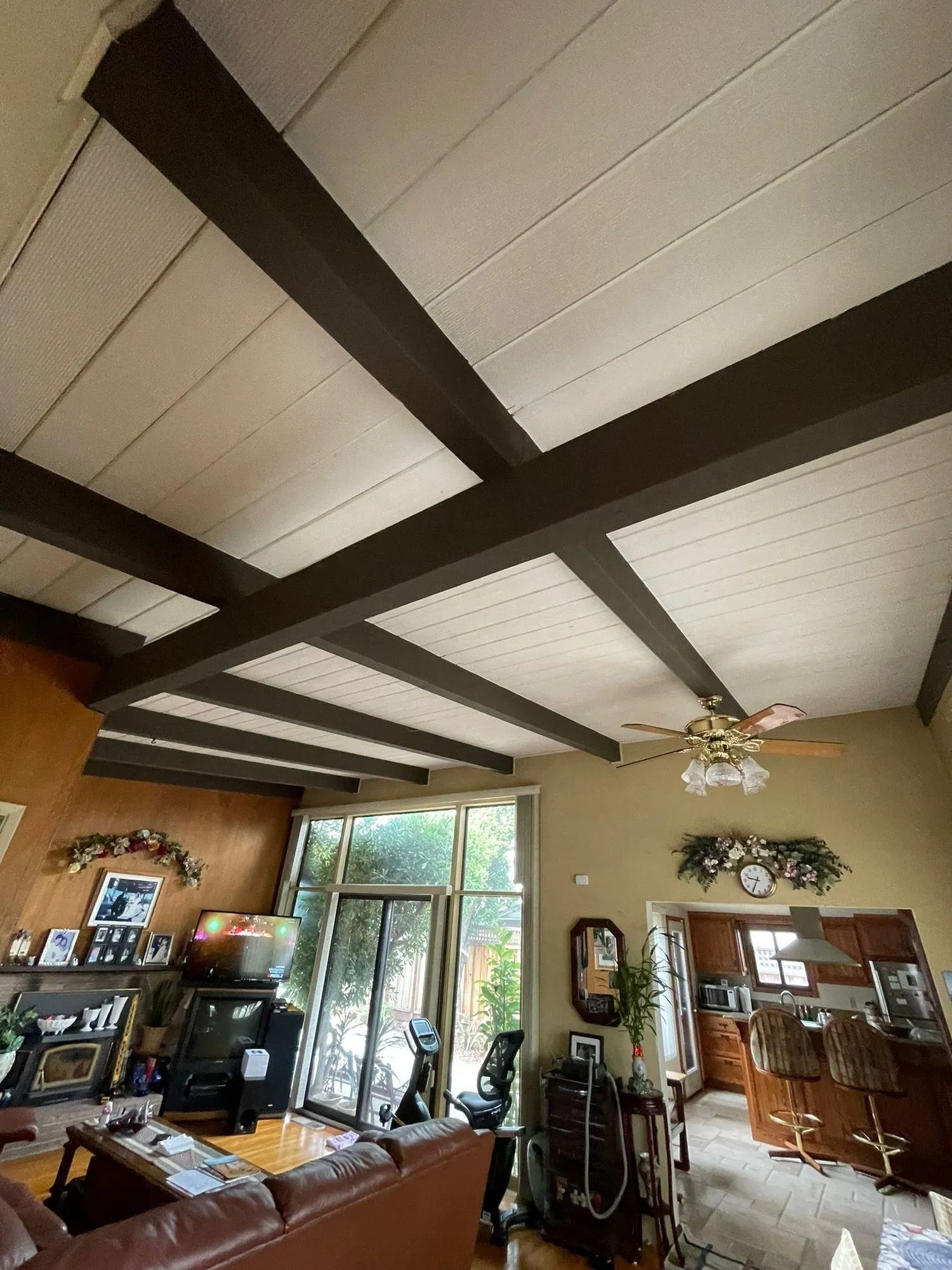 Original living space before remodel, dark-stained beams, wood panelling and patterned flooring
