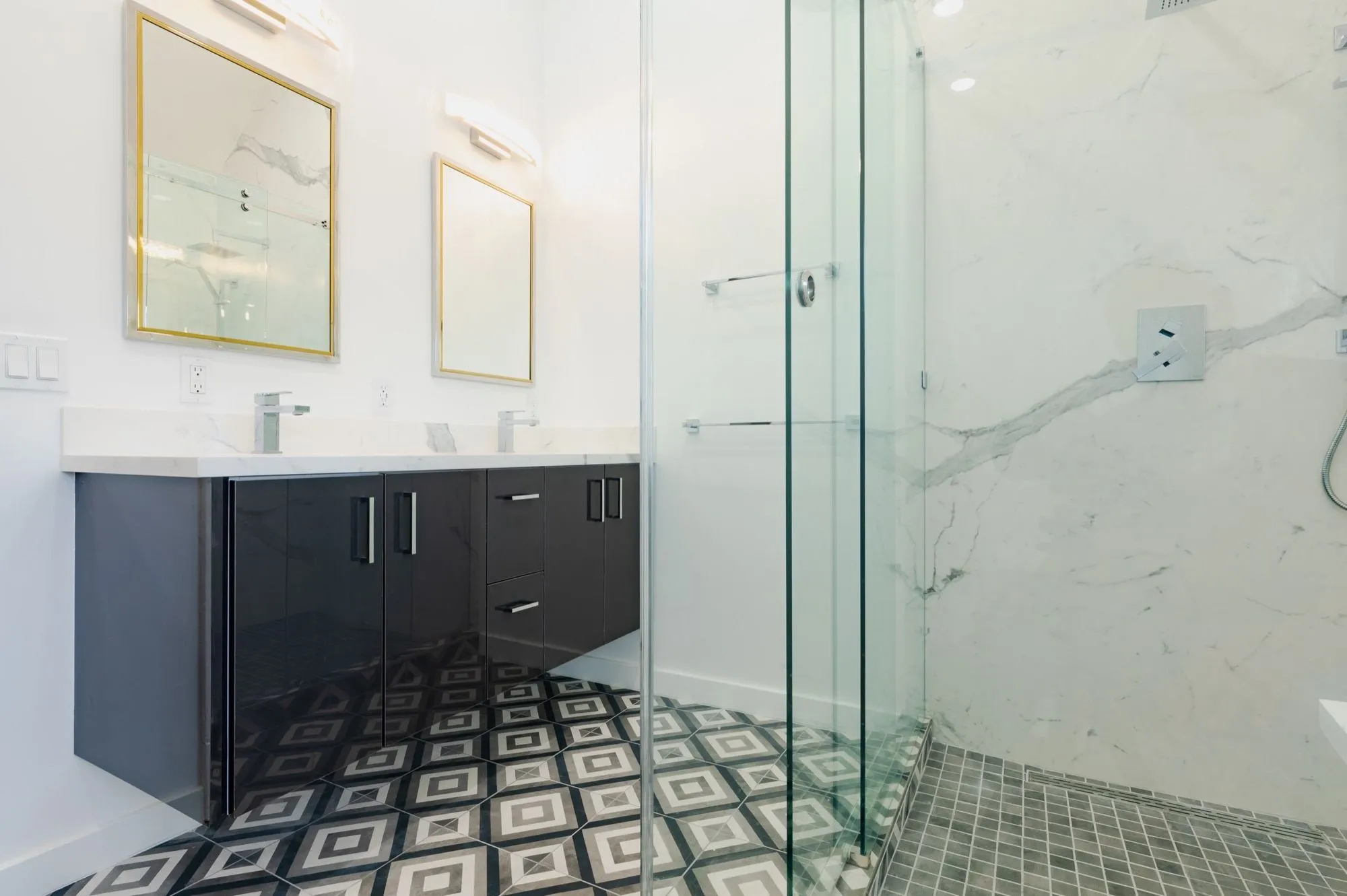 Navy gloss double vanity with brass-framed mirrors above geometric patterned floor tile