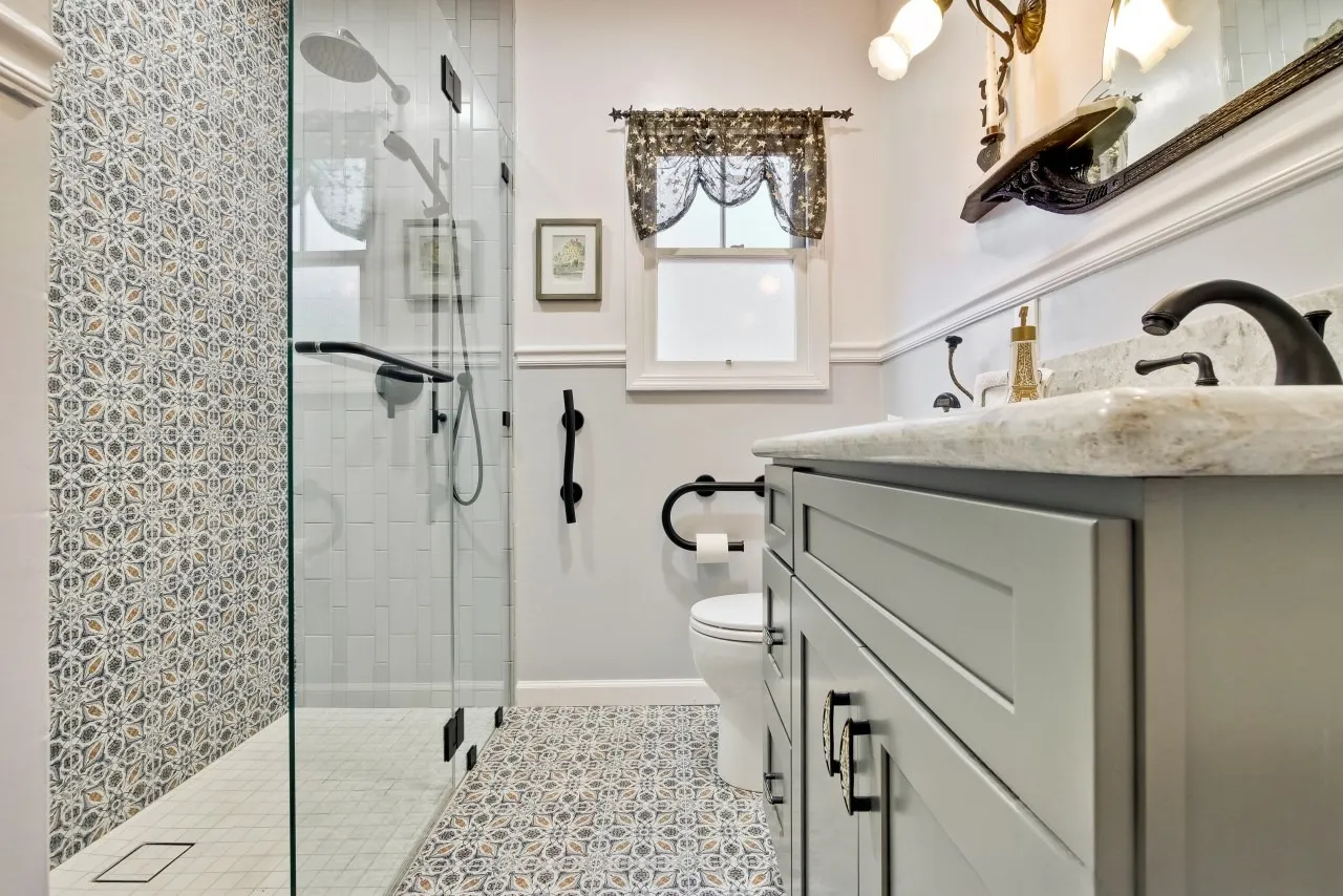 Patterned floor tile running to a glass shower with a matching patterned feature wall