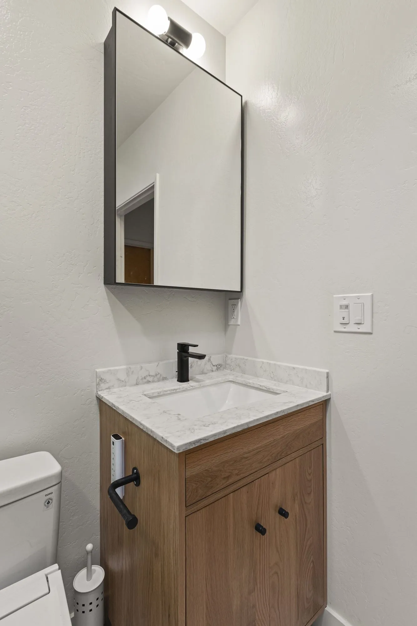Powder room vanity in timber with a black tap and a slim rectangular mirror