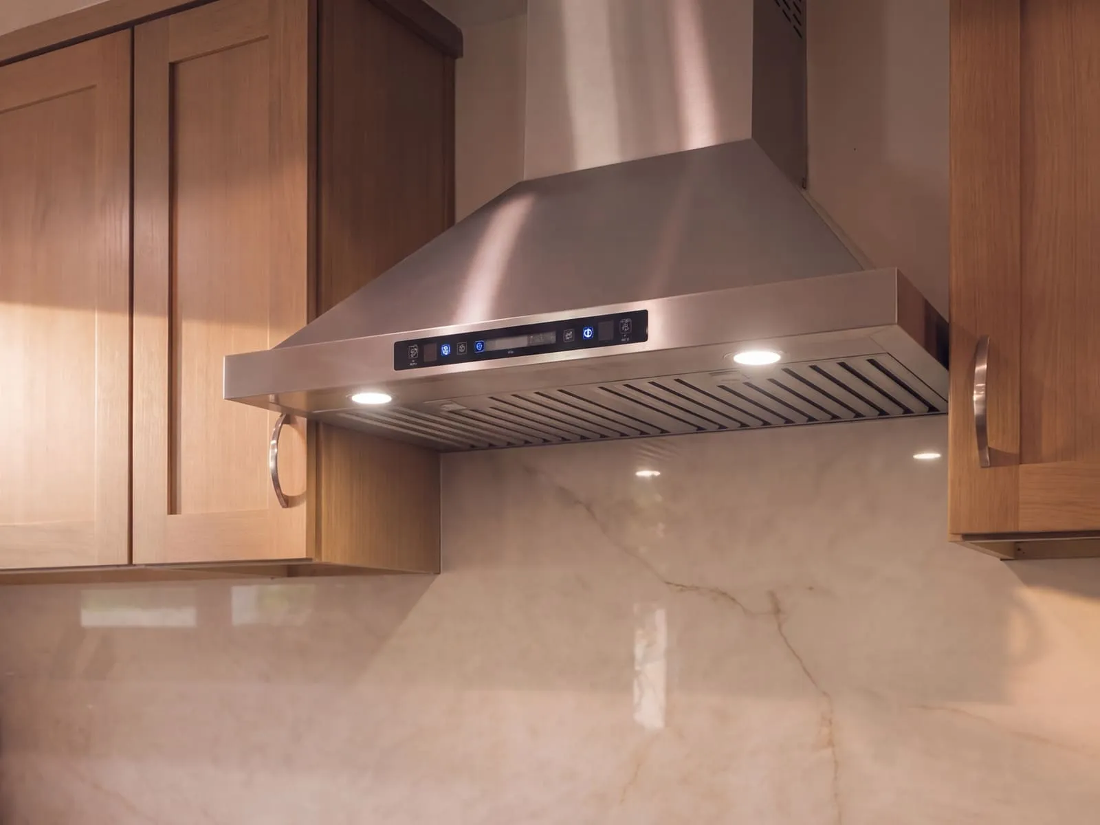 Close view of the stainless hood and the soft grey veining in the full-height quartz backsplash