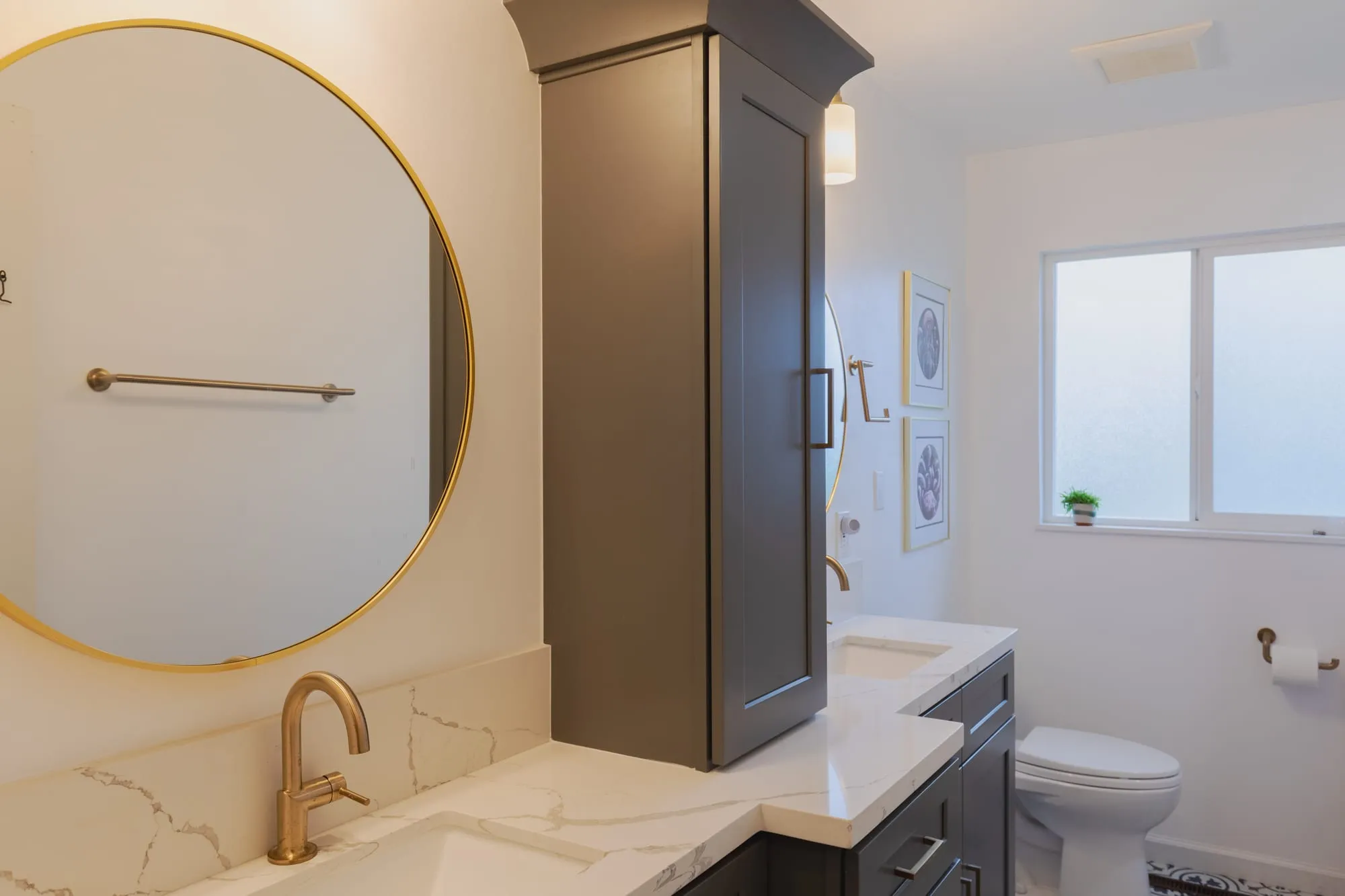 Round brass-framed mirror above a veined quartz counter