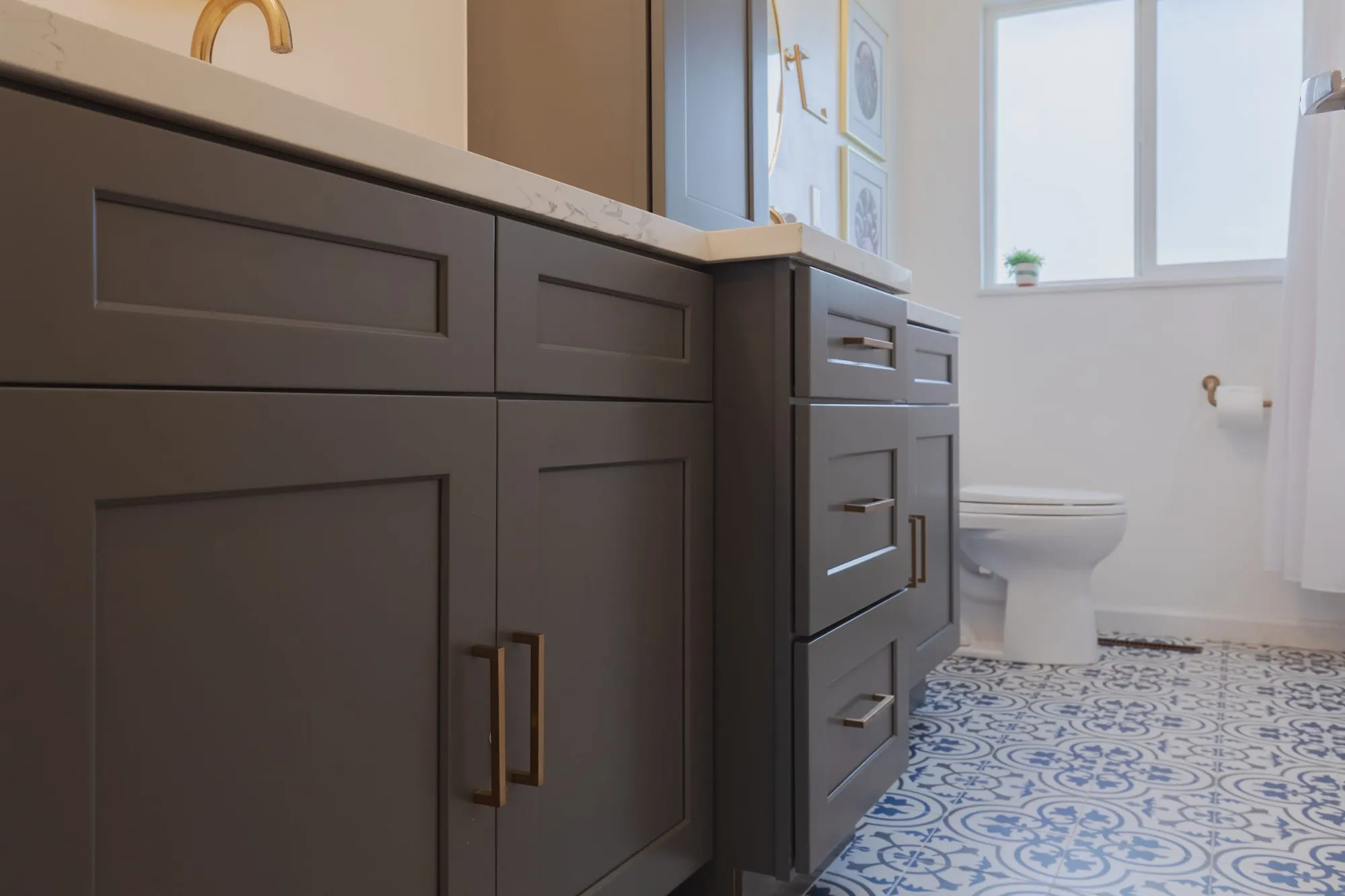 Grey shaker vanity with brass pulls beside a linen tower