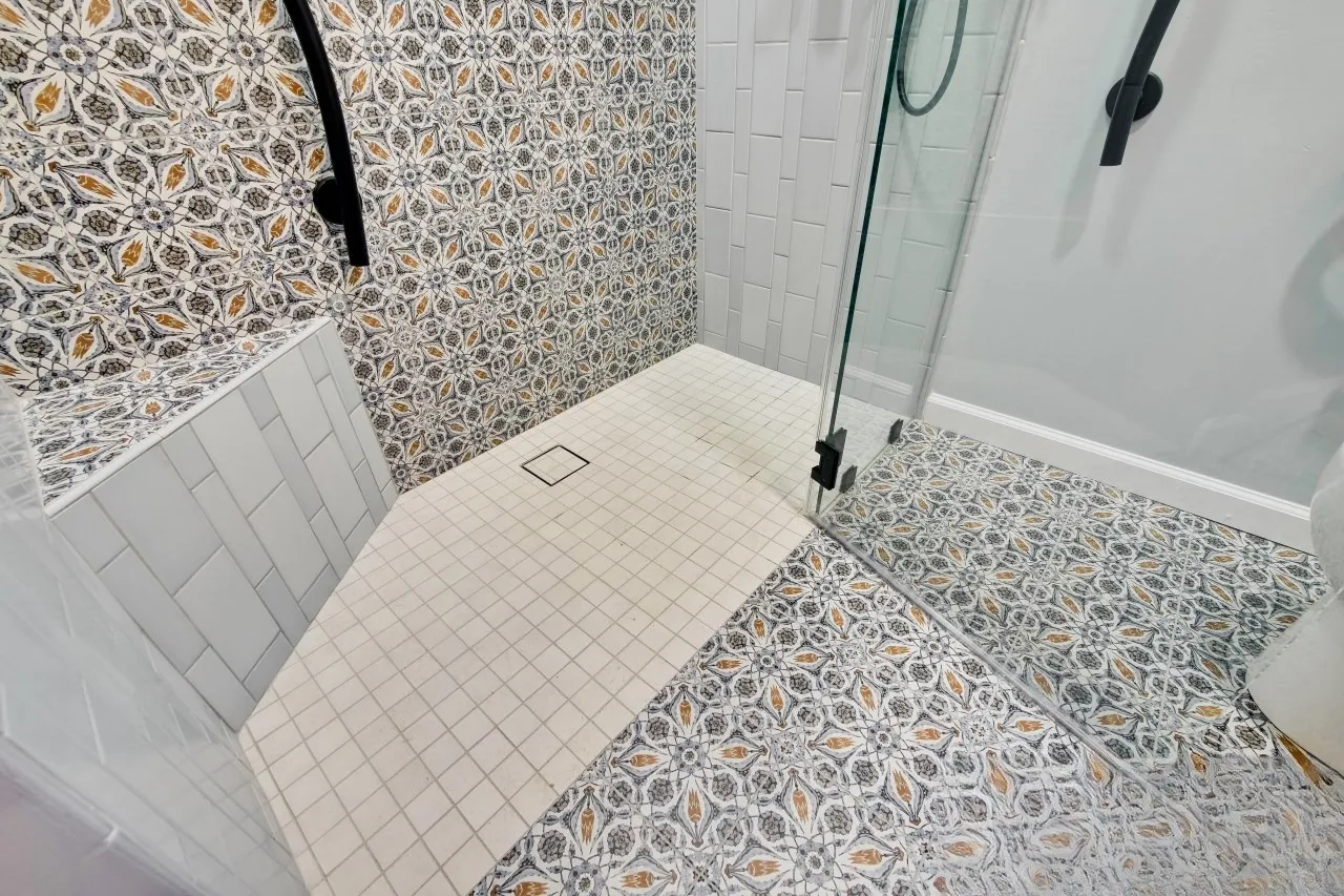Shower interior with a tiled bench, square mosaic shower pan and a low threshold at the entry
