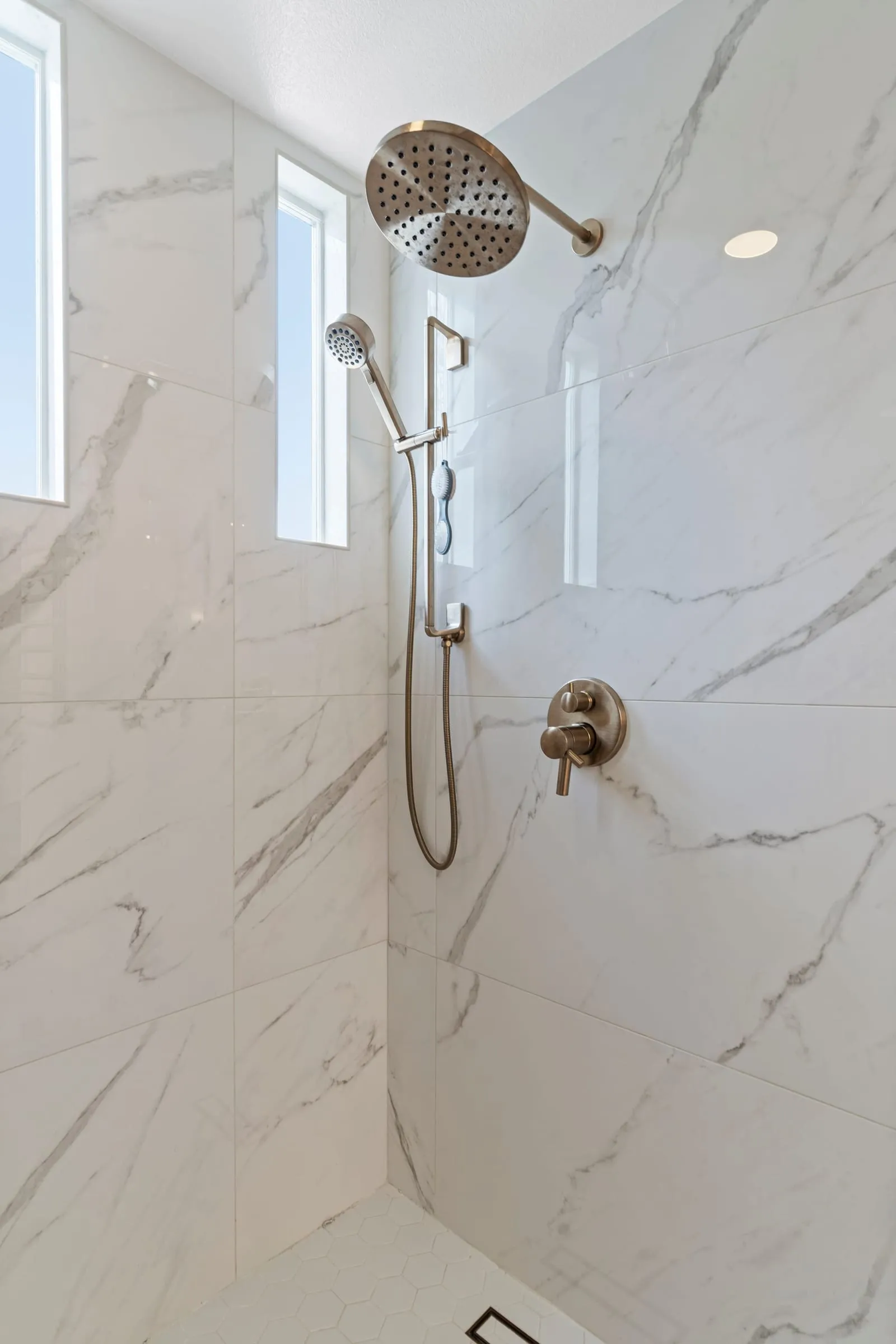 Brass shower controls against marble-look tile