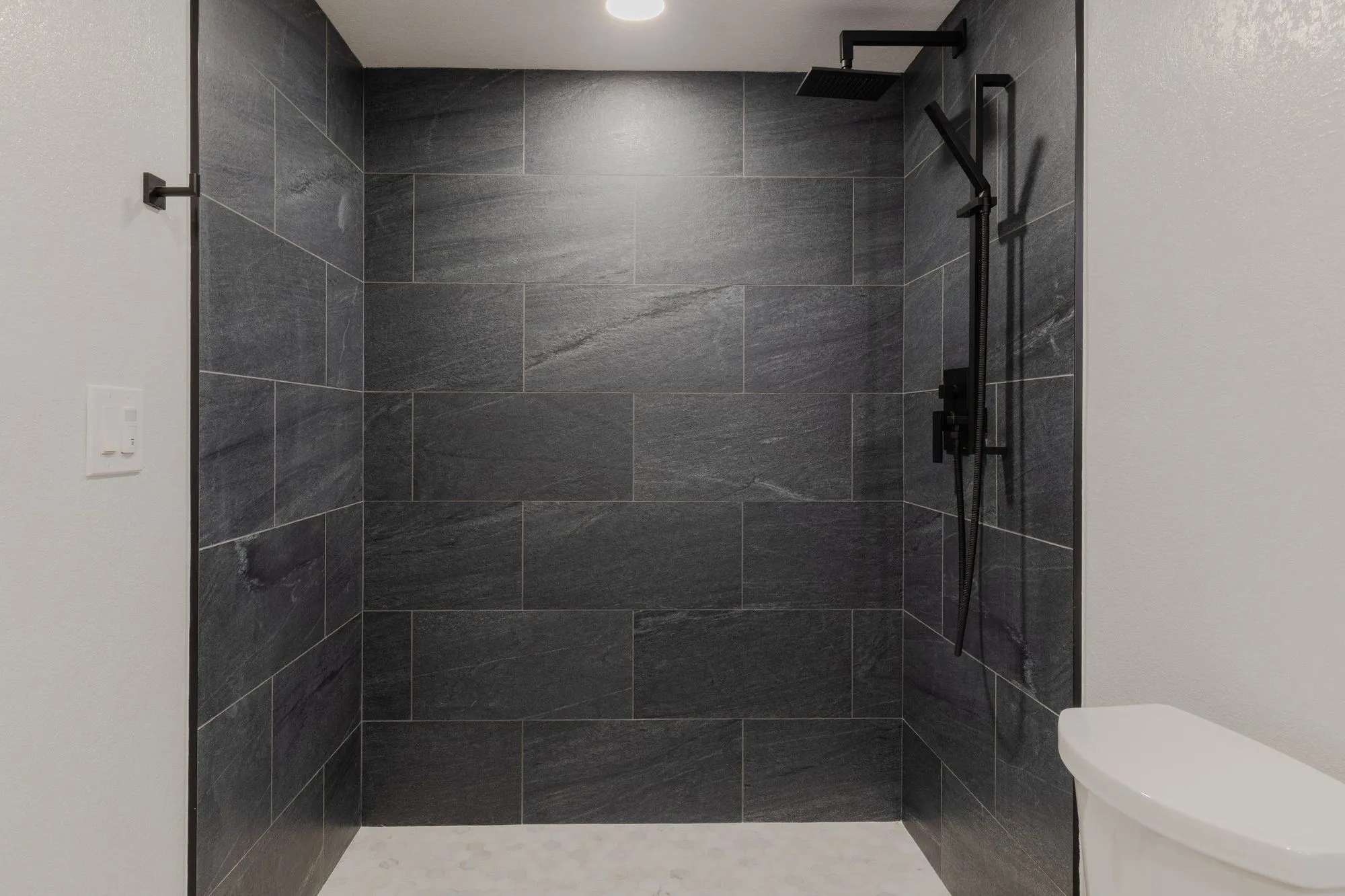Walk-in shower lined in dark stone-look tile with matte-black fittings