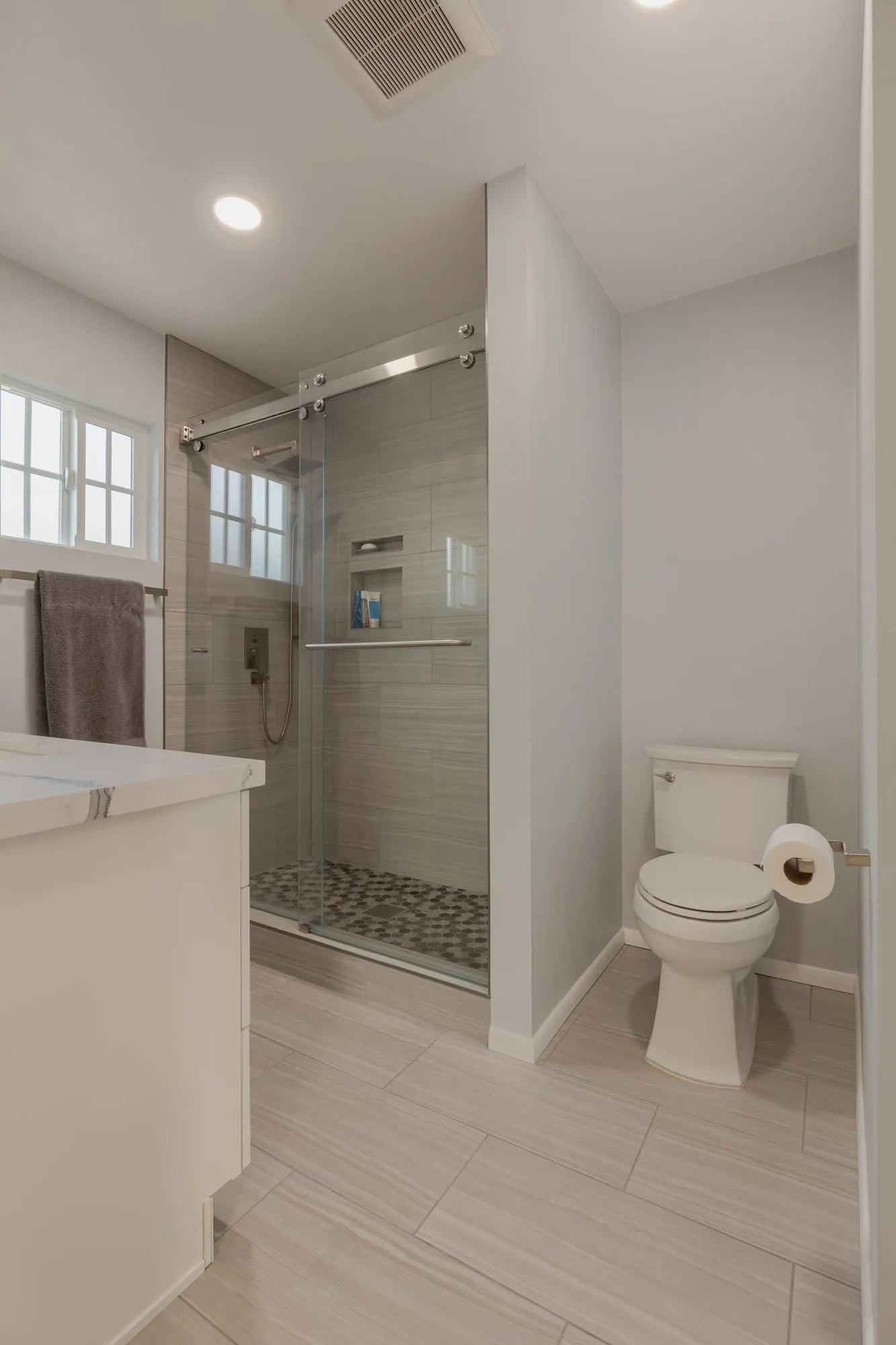 Shower behind a fixed glass panel beside the vanity run