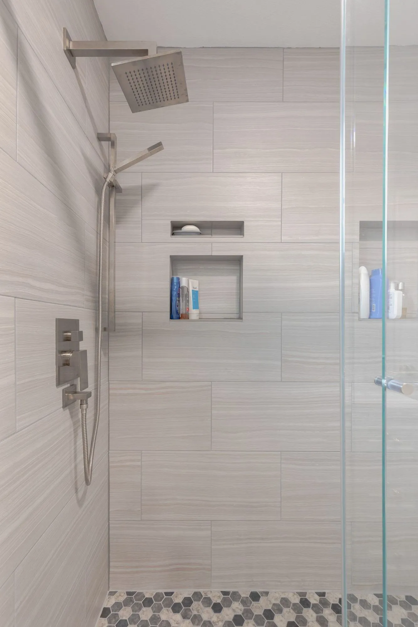 Walk-in shower with a hexagonal mosaic floor and a recessed niche