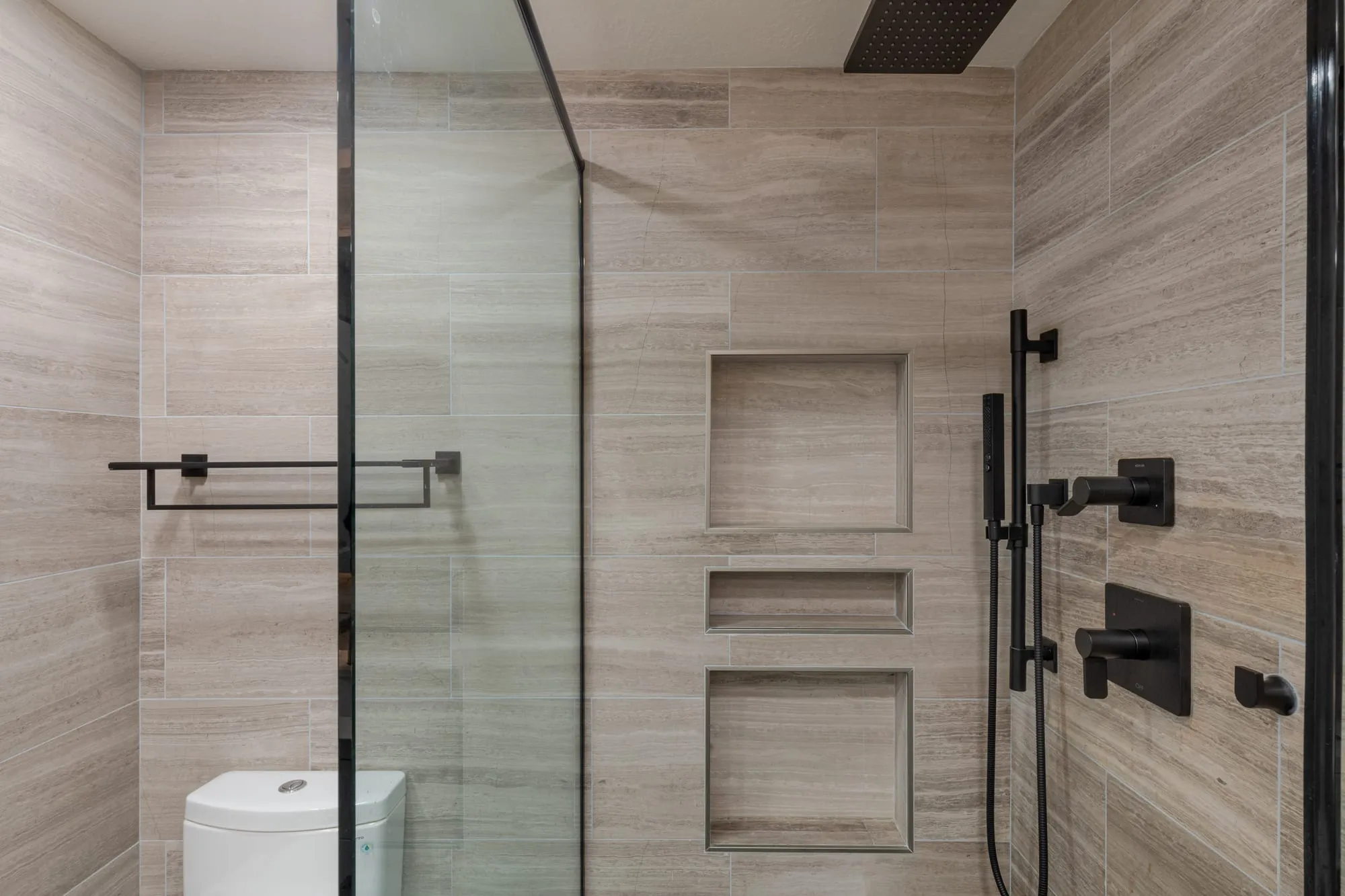 Glass shower with a stack of three recessed niches and matte black shower fittings
