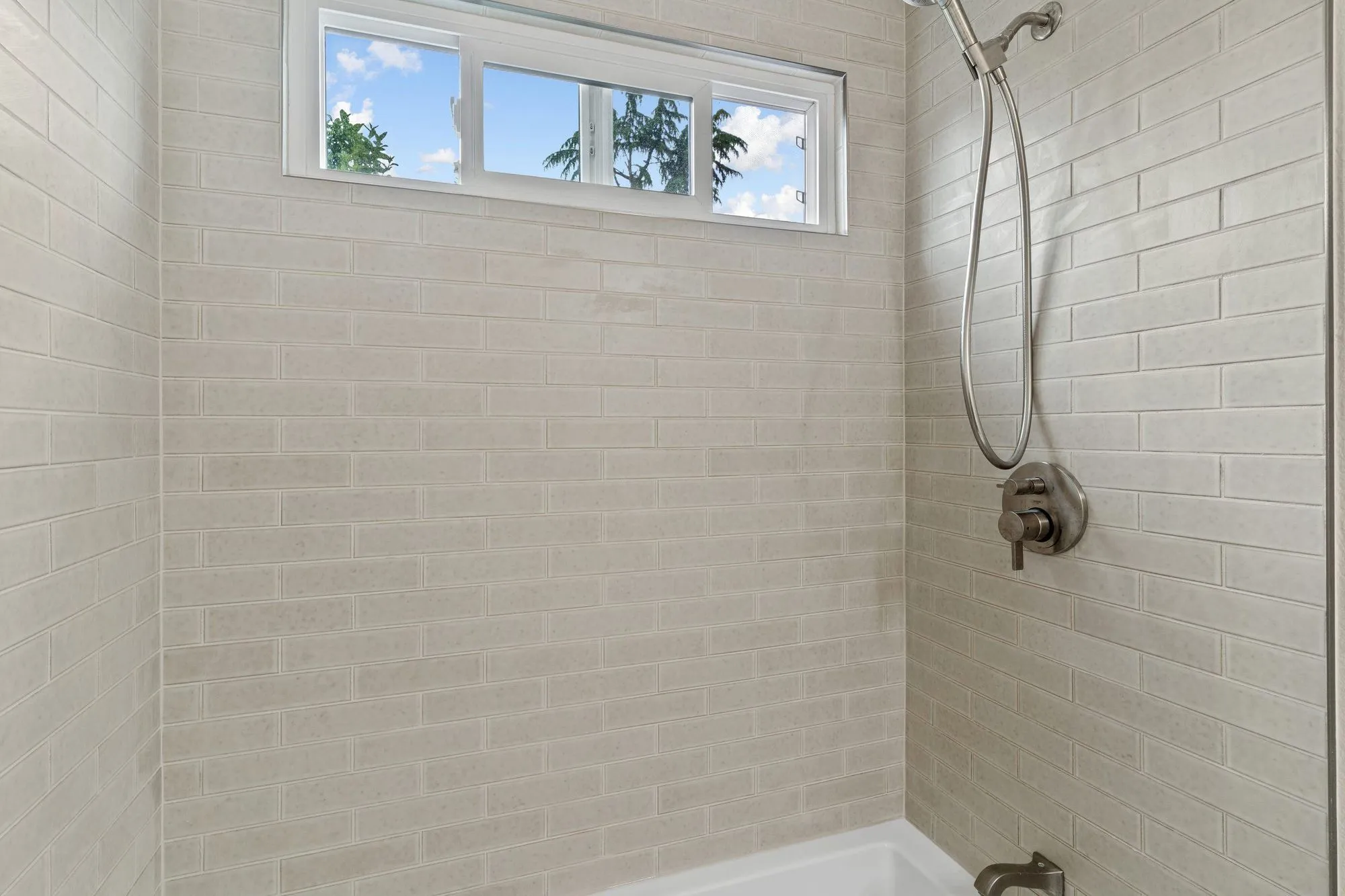 Shower wall in white subway tile with a recessed niche and chrome fixtures