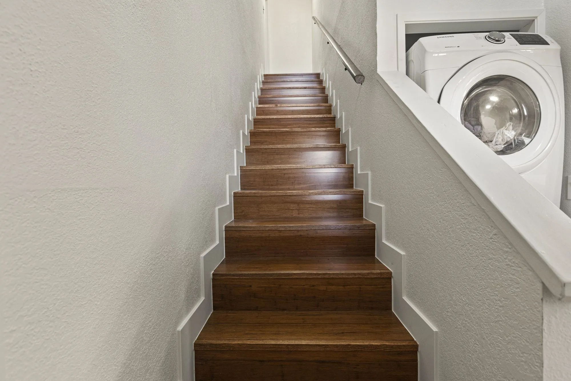 Straight stair run with timber treads and a slim wall-mounted handrail