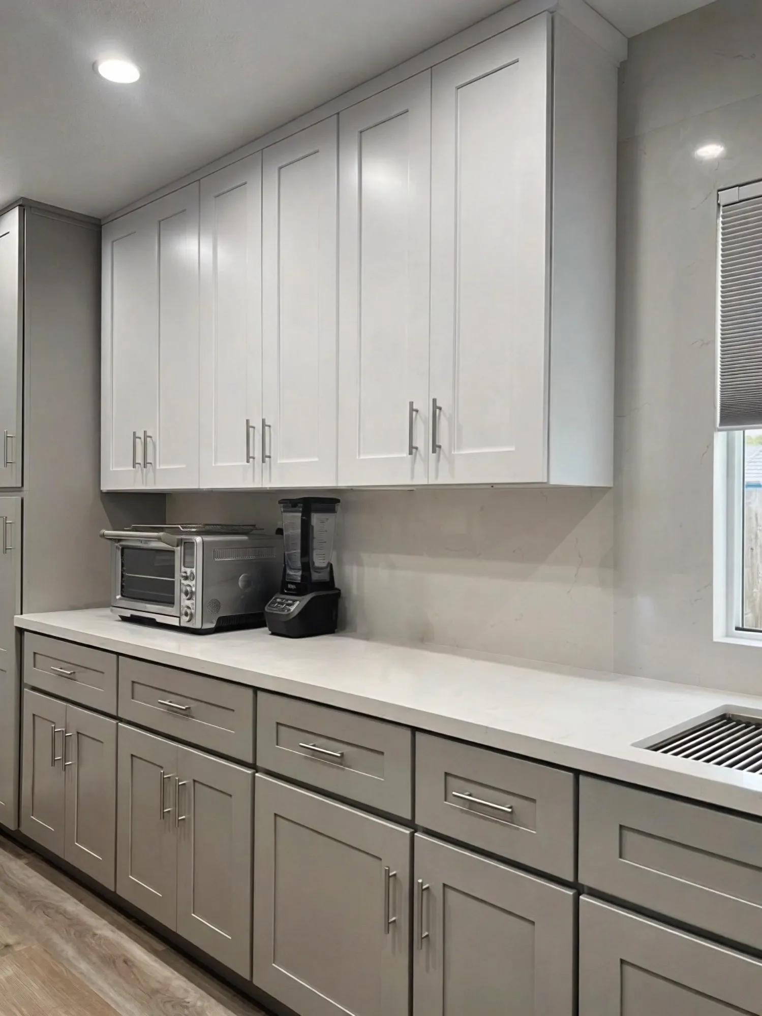 Two-tone cabinet run with bar pulls and the wall ovens beyond